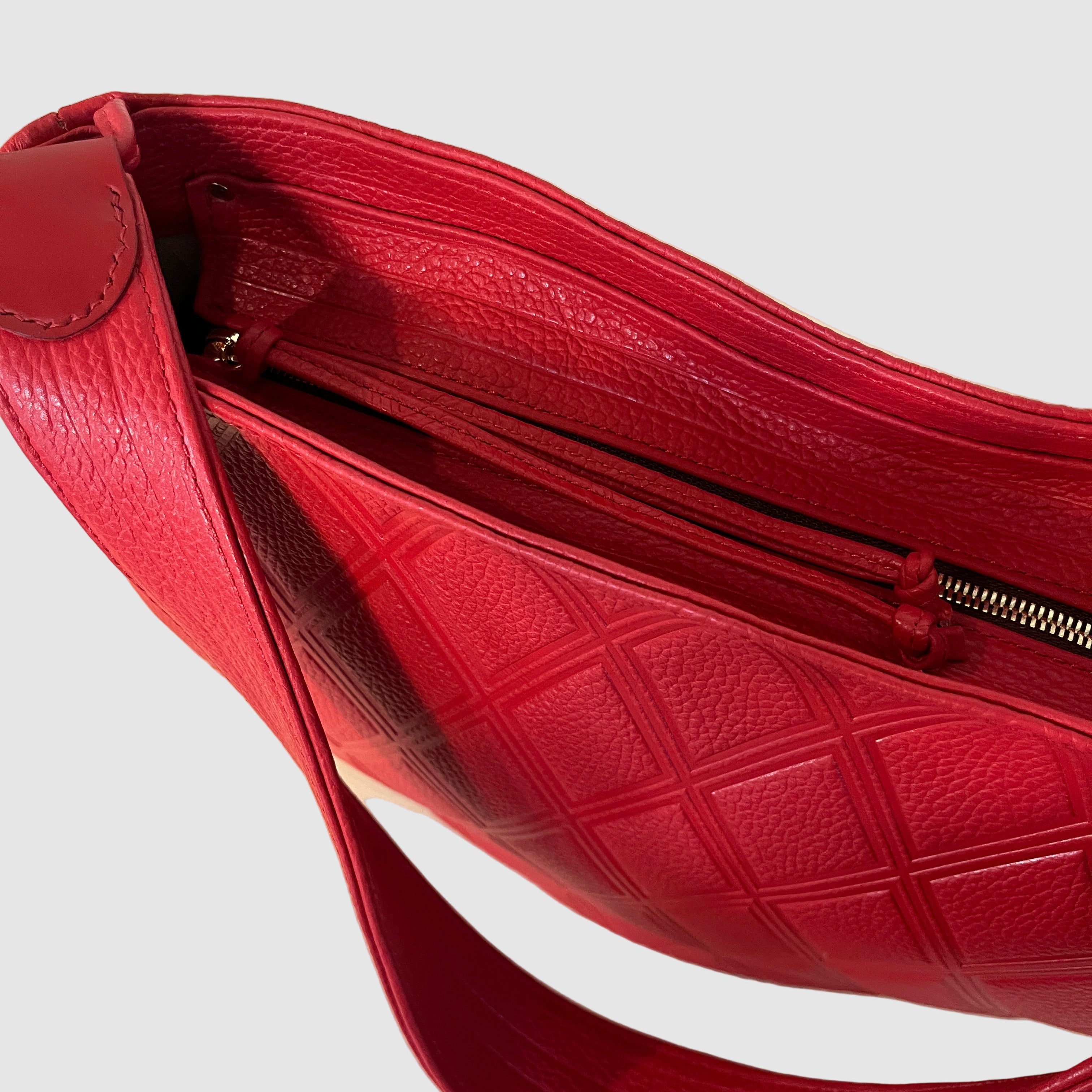 embossed red leather bag in quilt pattern with stripes on bottom gusset and zipper pull