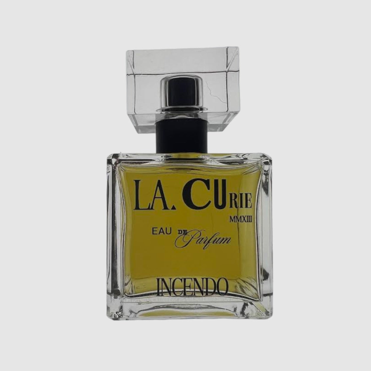 A square glass bottle with a black cap, labeled 'LA CURIE EAU DE PARFUM INCENDO'.