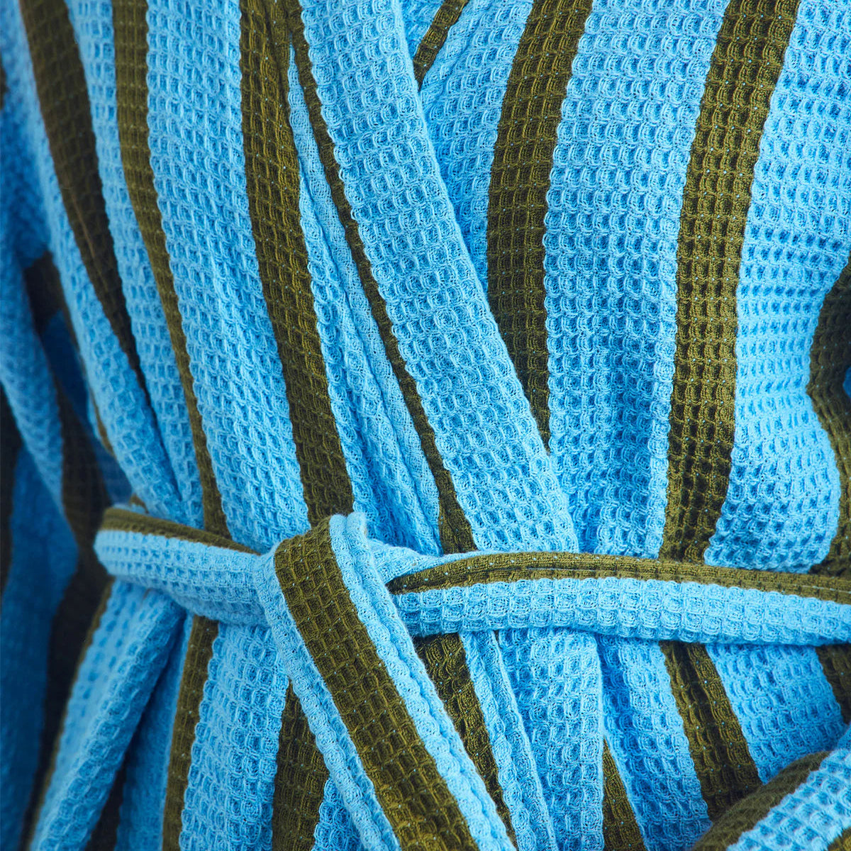 Close-up of a blue and green striped robe with a hand holding it.