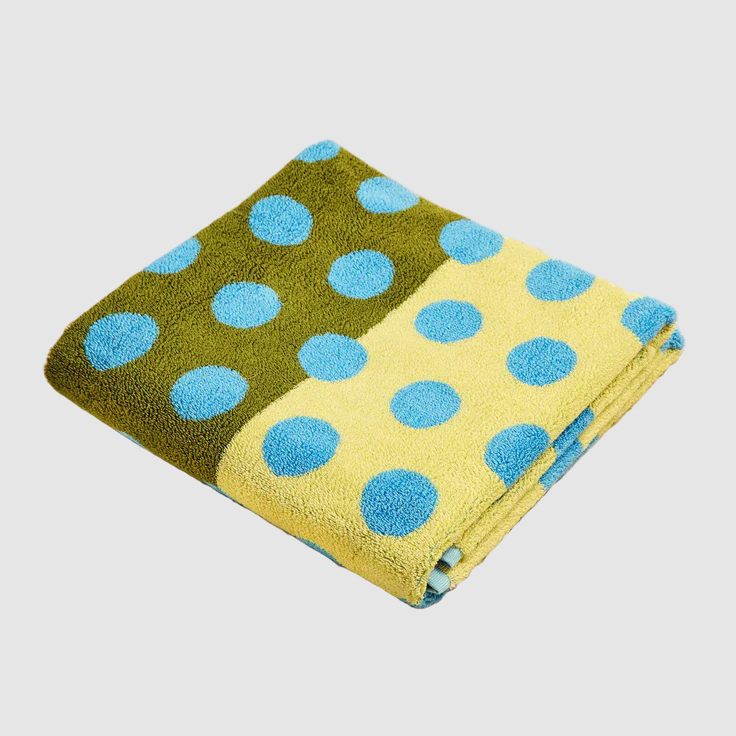Folded towel with green and yellow polka dot pattern on a beige surface
