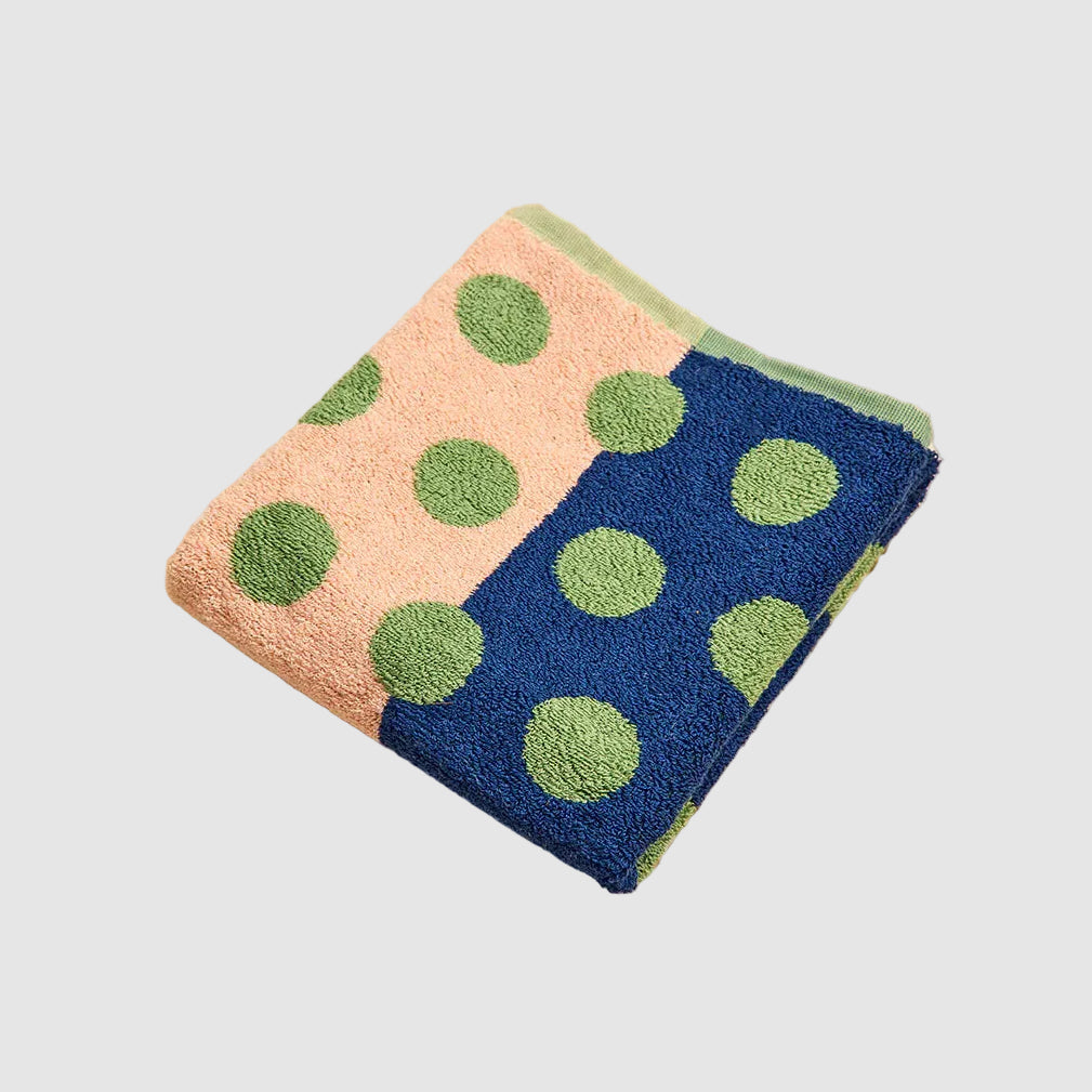 Folded towel with green polka dots on a beige surface
