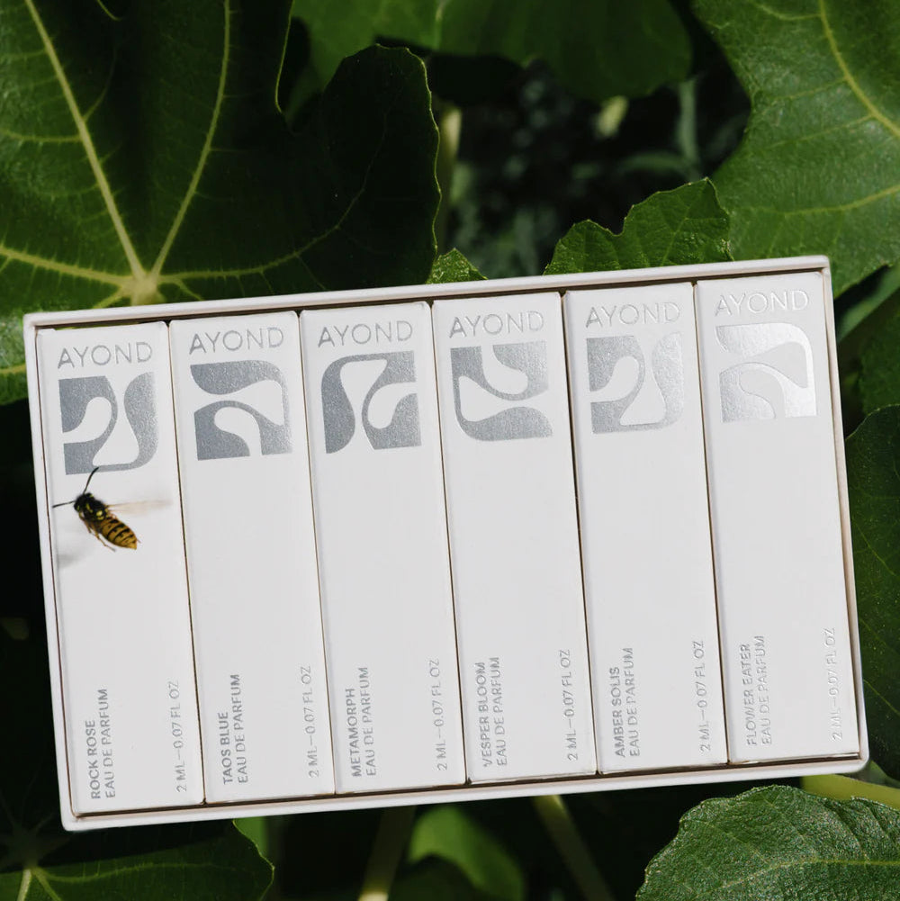 Row of Ayond perfume samples on green leaves with a wasp.