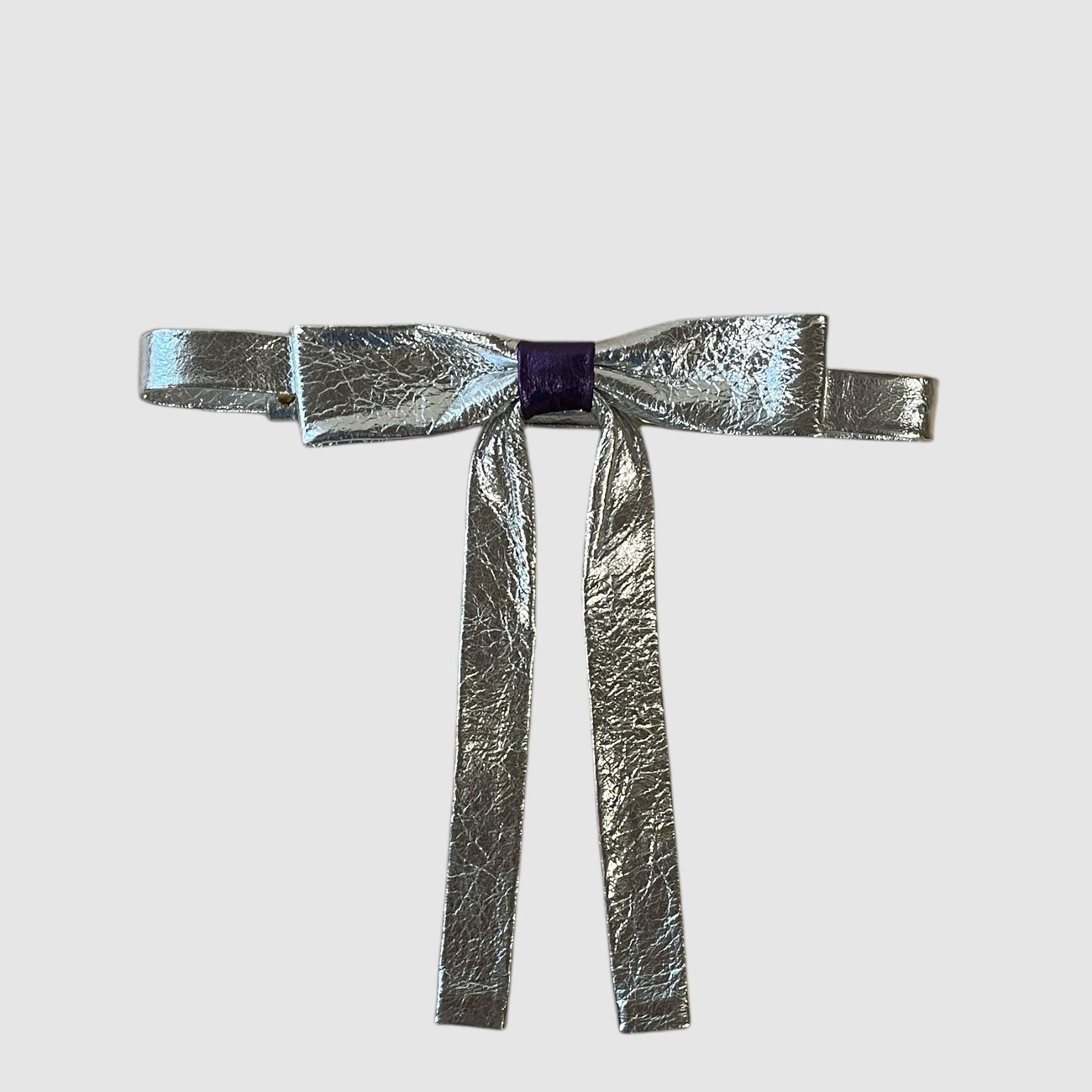 A metallic silver neck bow with a purple middle wrap and a small brass buckle closure, displayed against a white background.