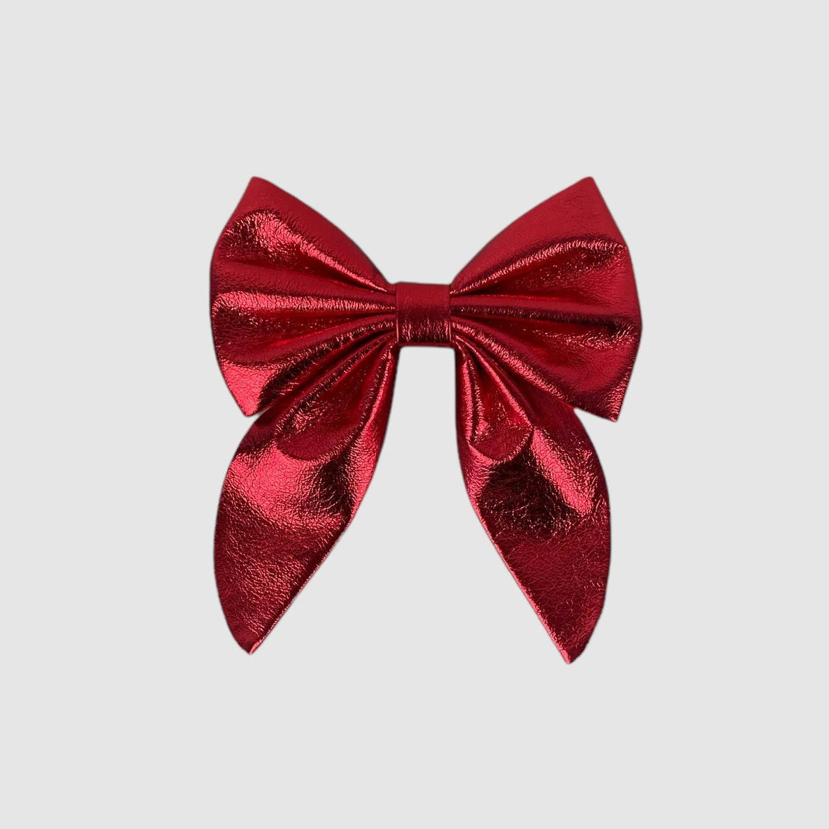 A red metallic leather neck bow with a small brass buckle closure.