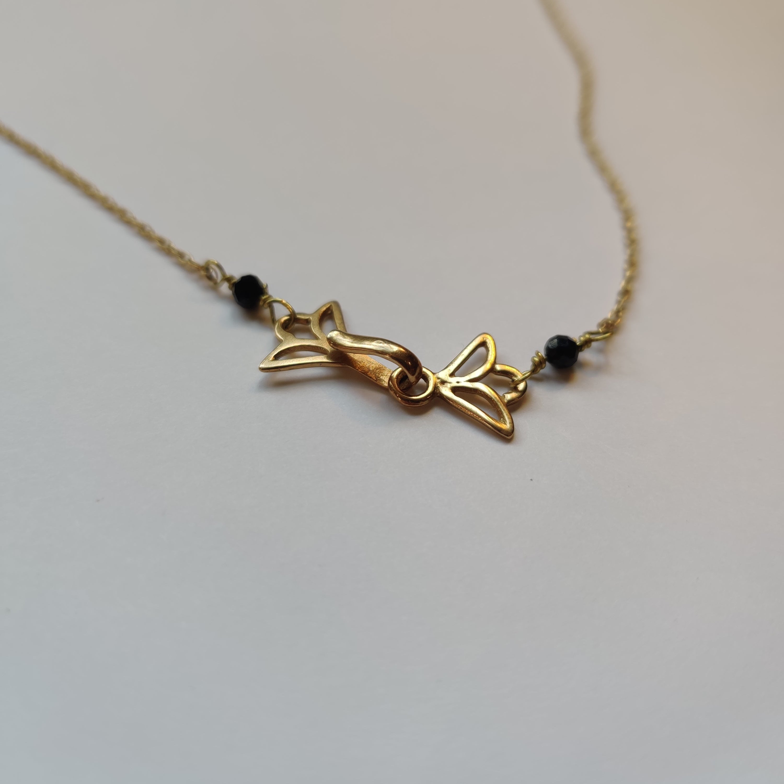 Gold necklace with a decorative pendant on a light background