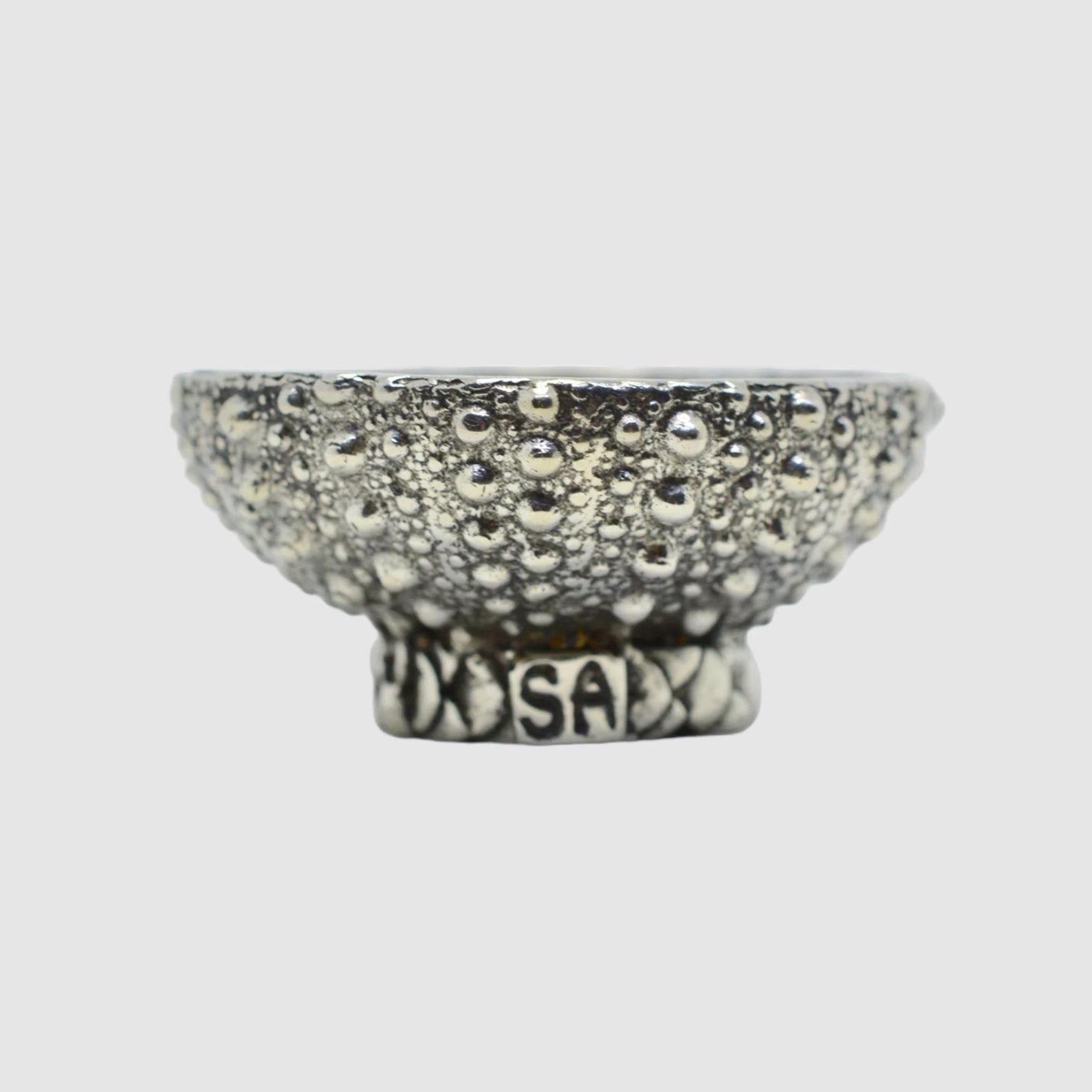 A medium-sized pewter bowl with a textured surface, resting on a flat base with the artist's signature 'SAL' visible on the side.