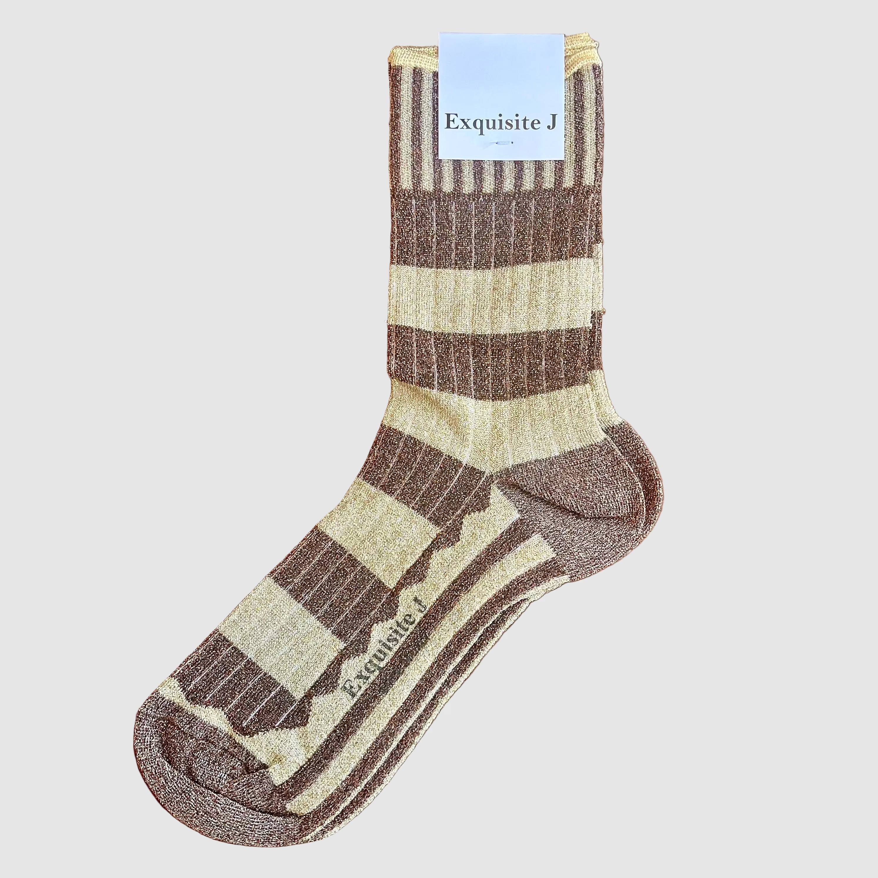 A single ribbed crew sock laid flat on a wooden surface, with a white paper tag at the cuff reading Exquisite J. The sock has wide horizontal stripes in warm beige and medium brown, with a tonal heel and toe.