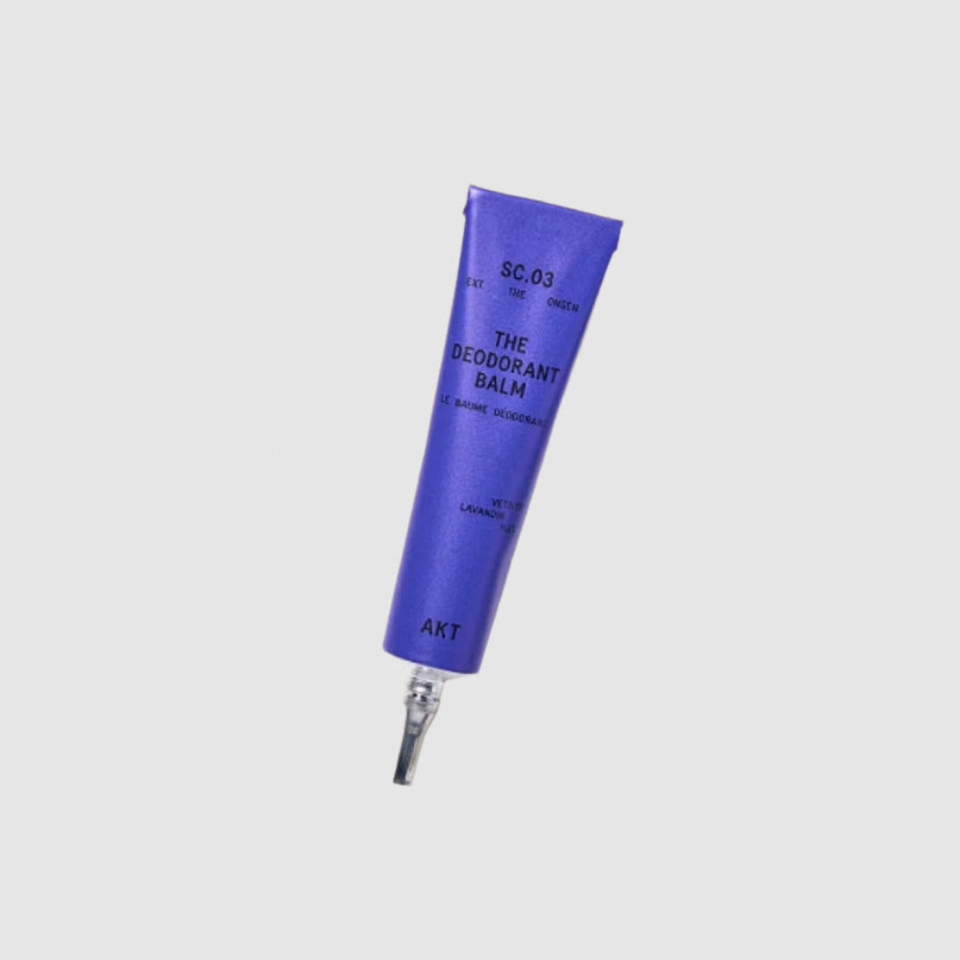 Mini deodorant balm tube labeled 'The Deodorant Balm' by AKT on a light gray background