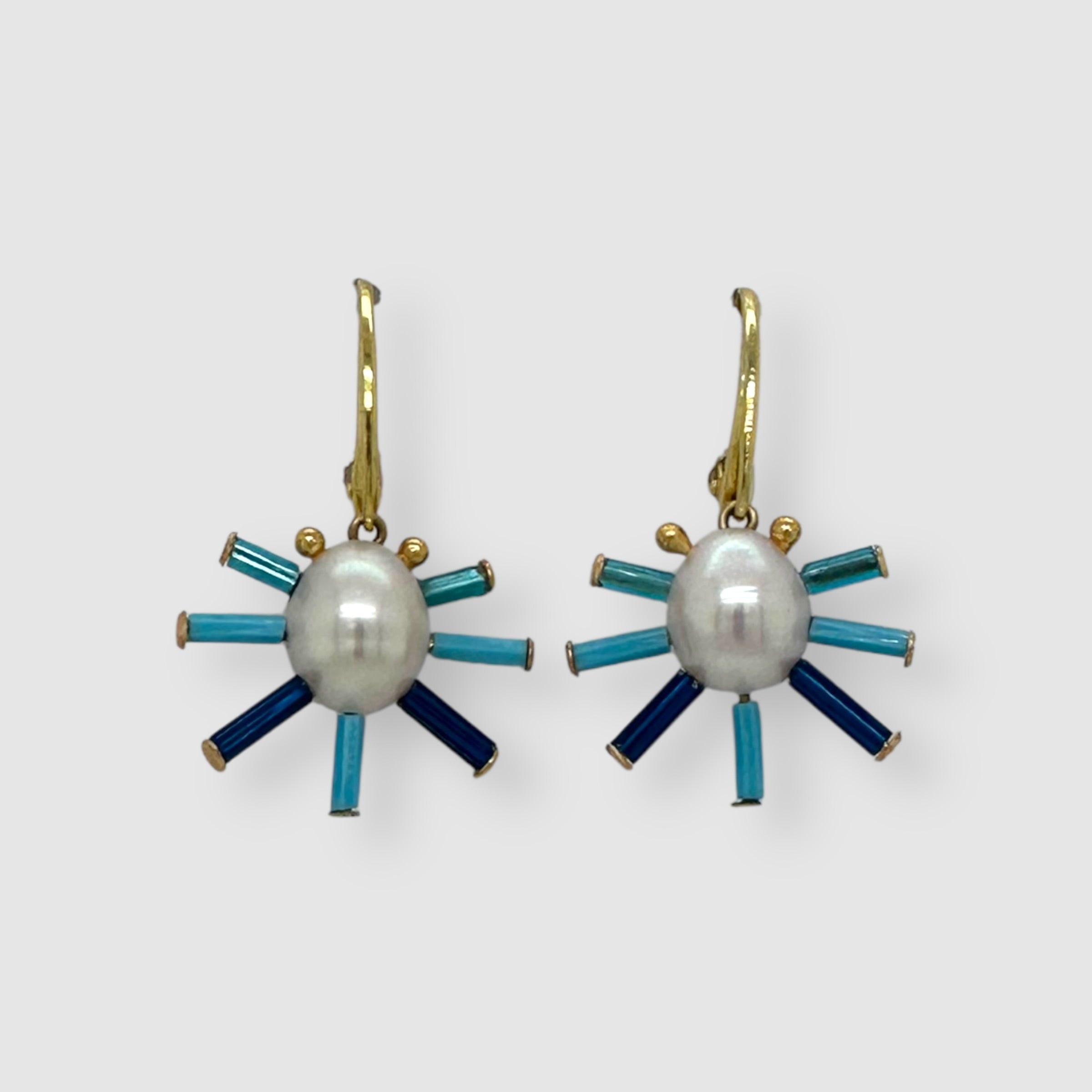 Pair of earrings handmade by Sofie Albertsen in Tucson, Arizona. Pearl center with vintage glass beads strung on a vemeil leverback clasp. Displayed on a light grey background.