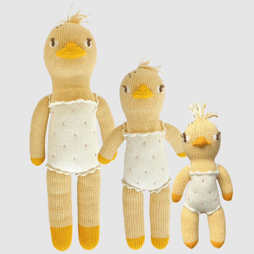 A set of three cotton knit dolls in the shape of ducks, in varying sizes, with white shirts and yellow details.