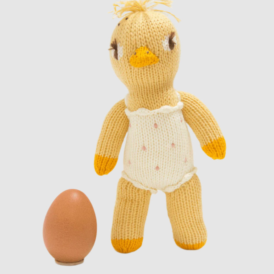 Knitted duck toy with a brown egg on a white background