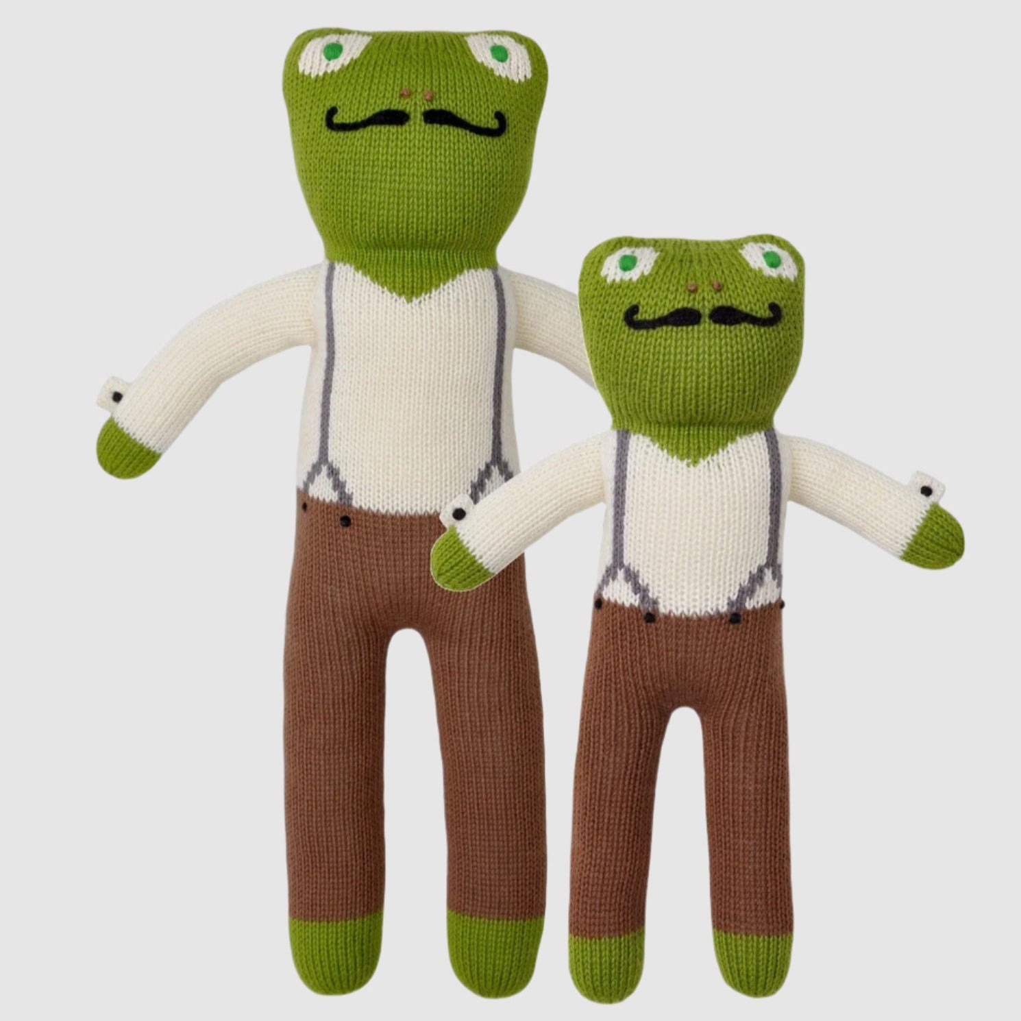 Two knit dolls designed to look like frogs, with green heads, white shirts, and brown pants. One larger and one smaller.