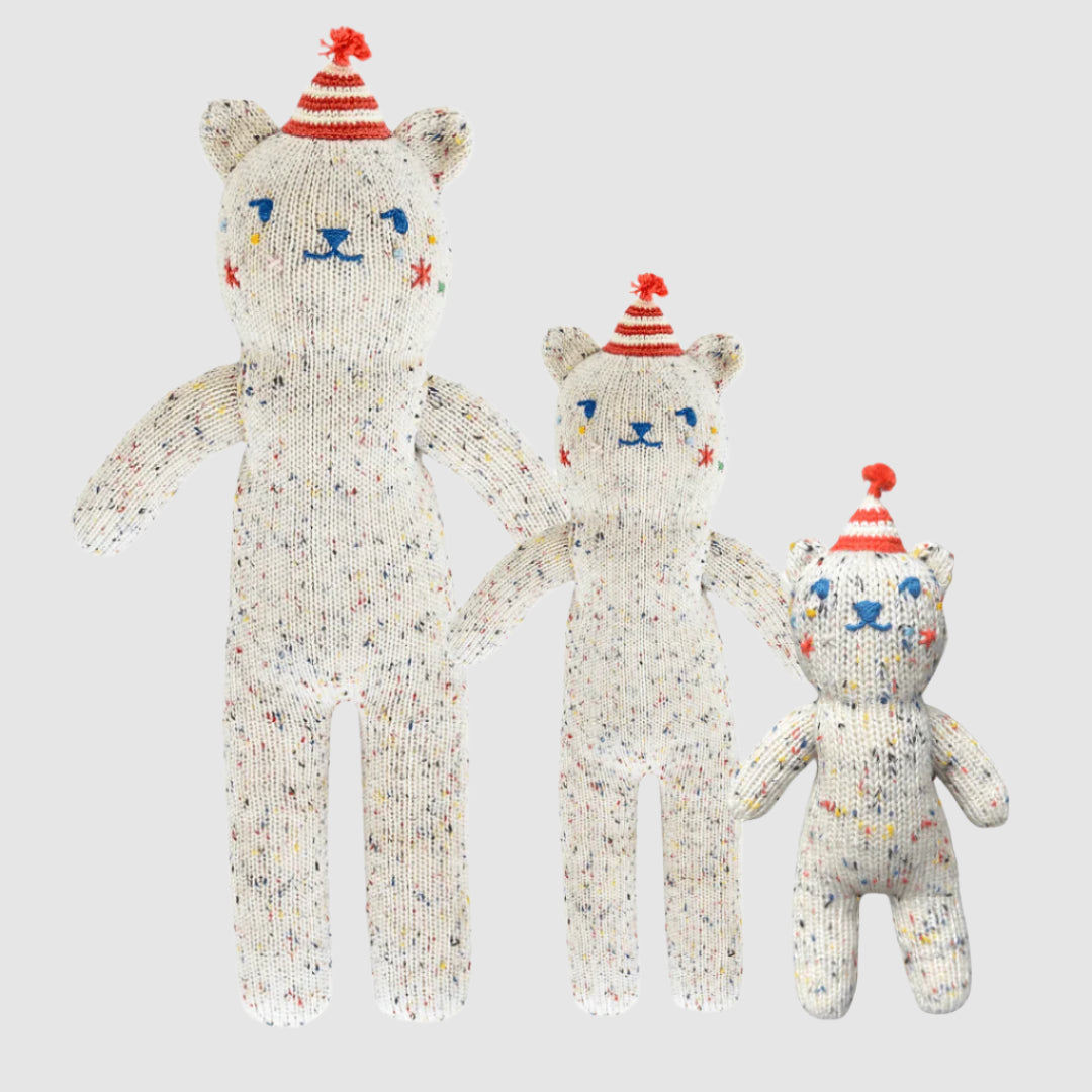 Three knitted teddy bears with colorful hats on a white background