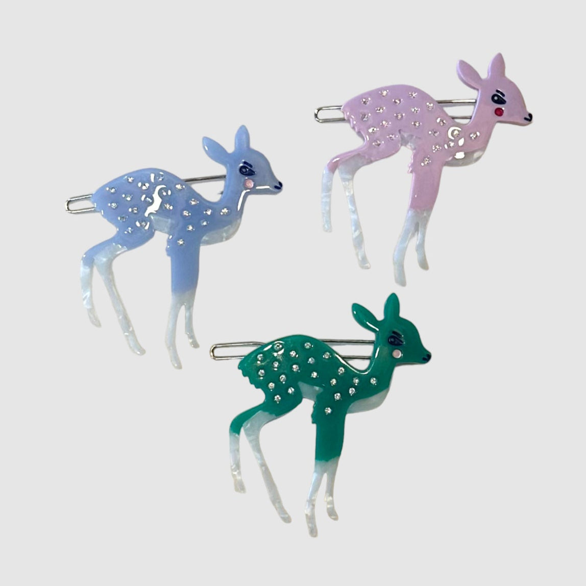 One green, one blue, and one pink, Centinelle, deer barrette on a light grey background