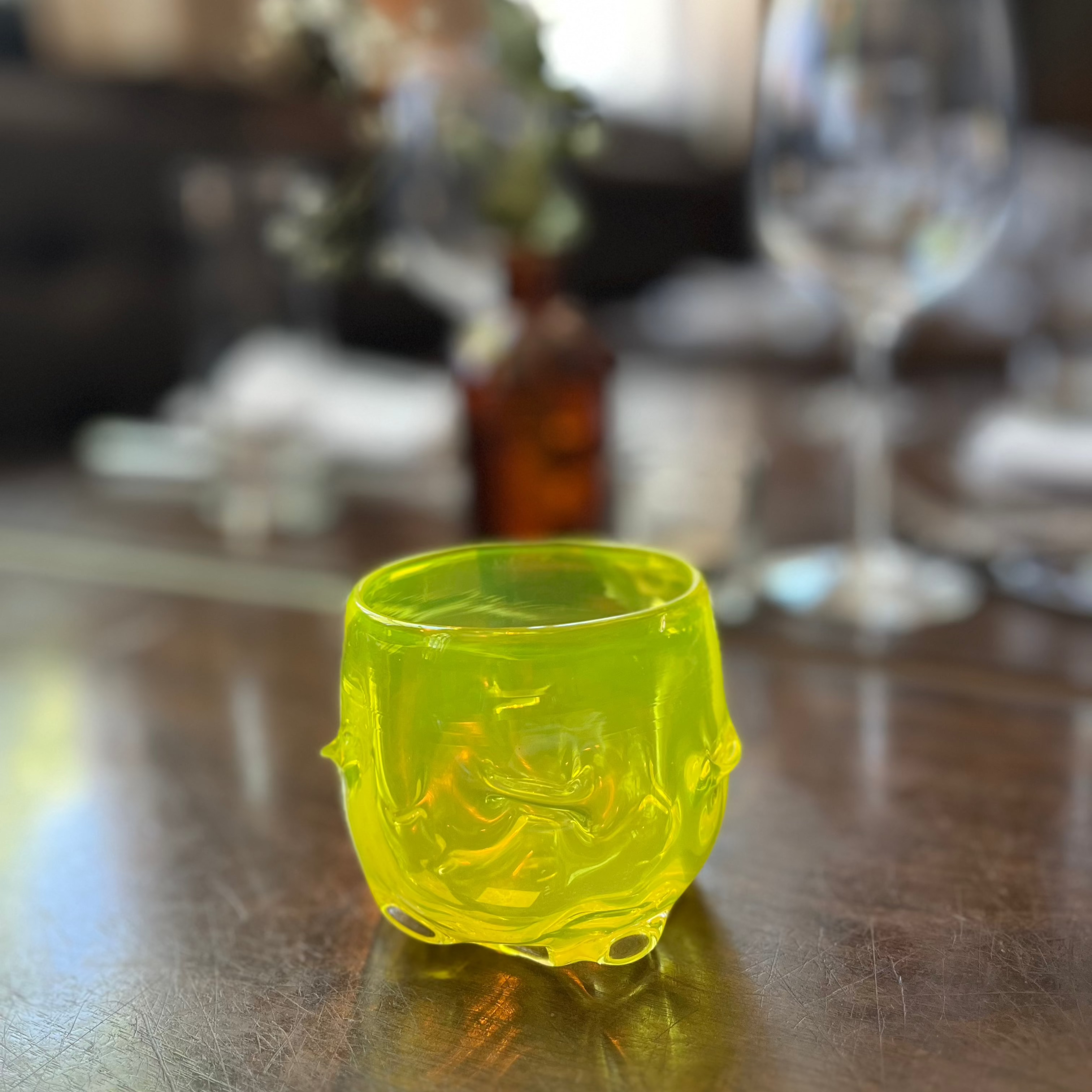 Yellow glass cup on a wooden table with blurred background