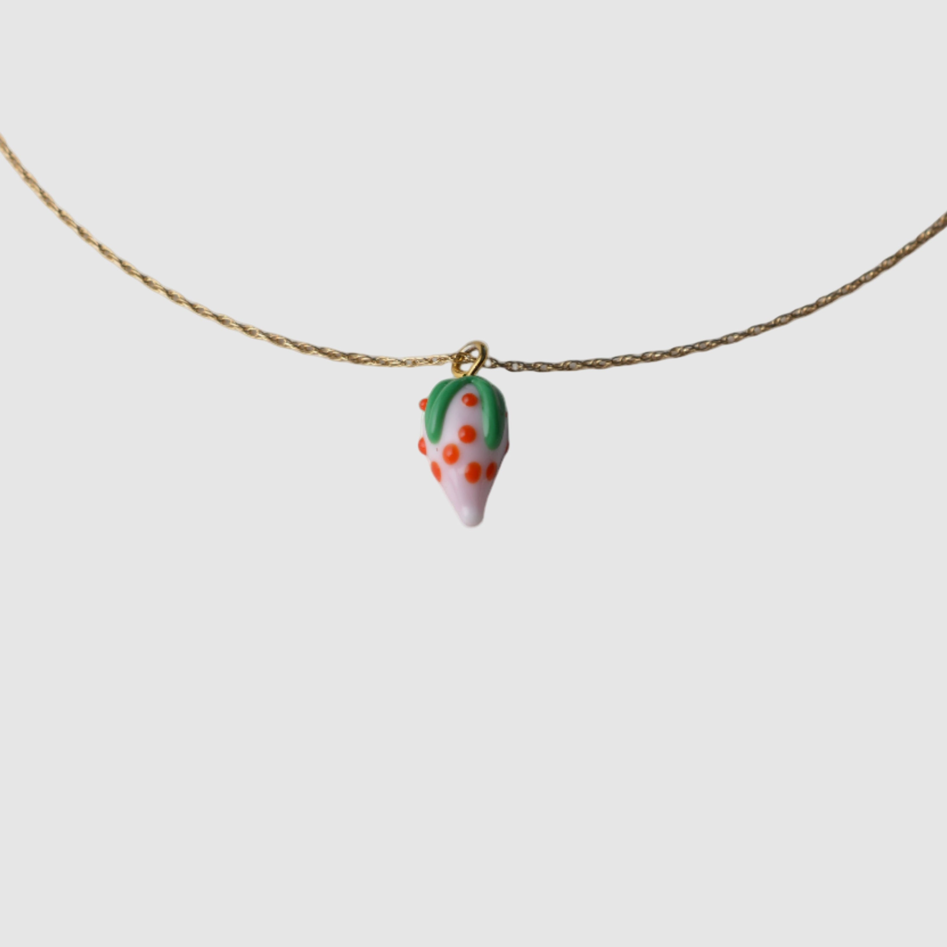 Handmade necklace with a small glass strawberry pendant on a plain background