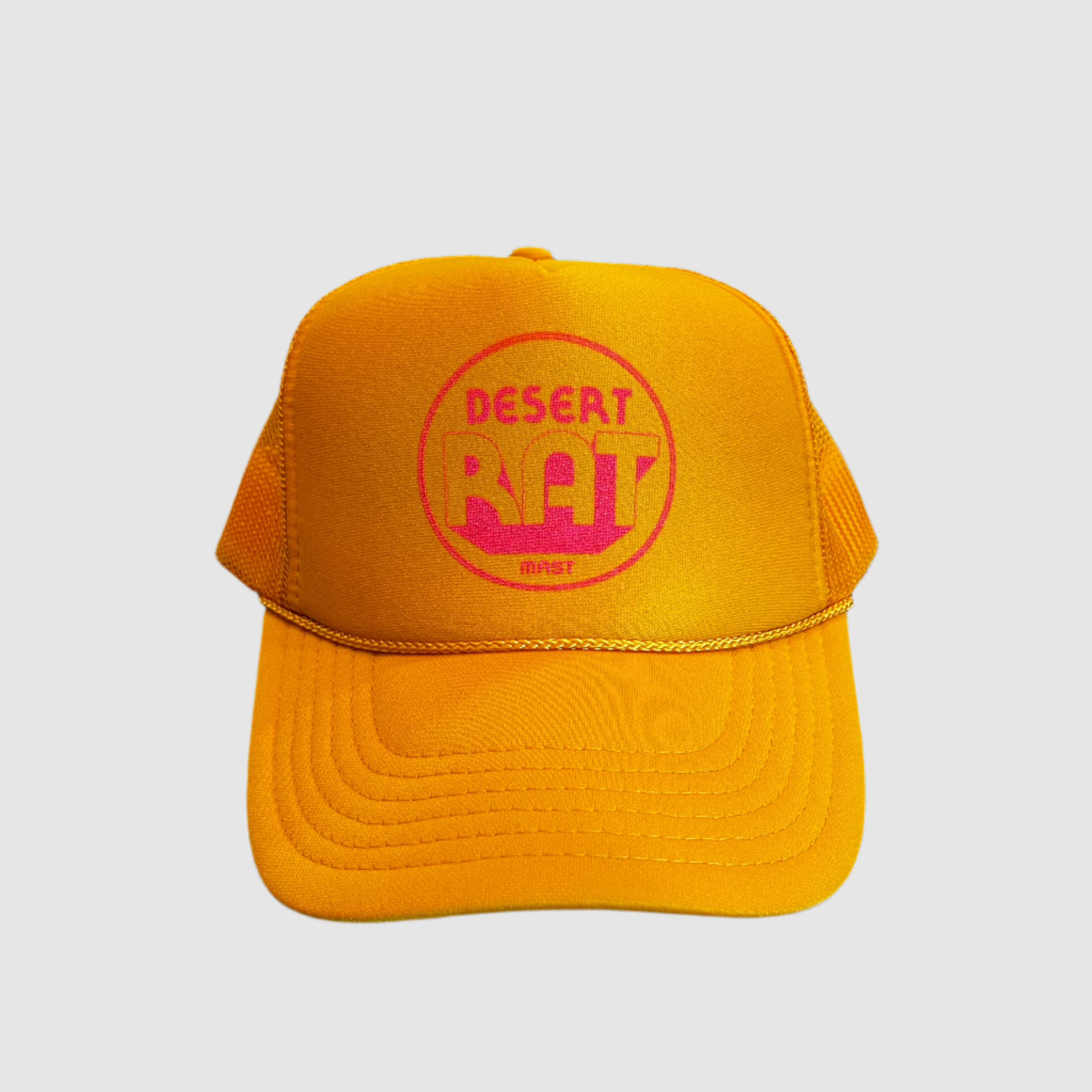 Front view of a yellow truckers cap with a pink, circular "desert rat" logo on front with "MAST" small underneath logo. Light gray background