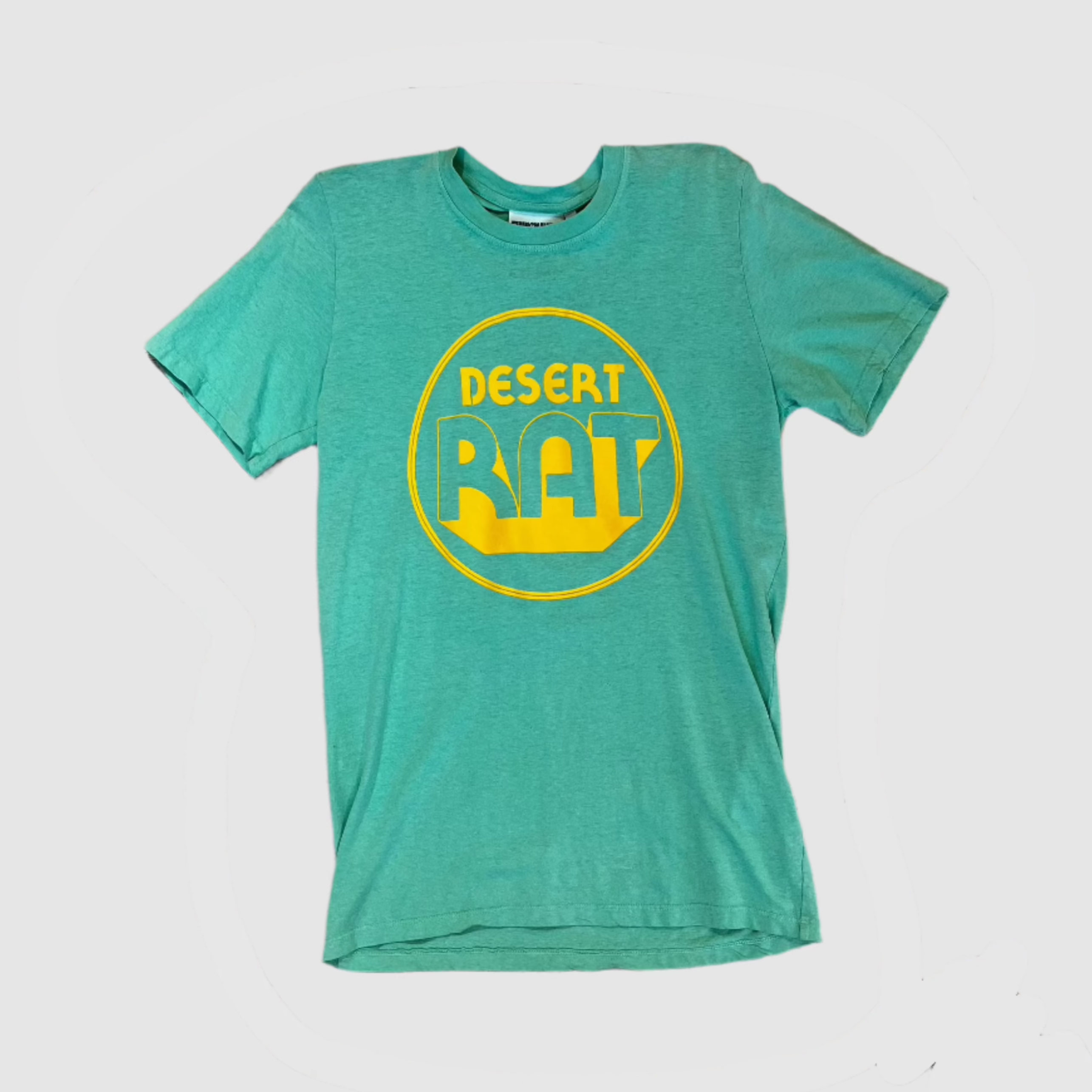 Front of a seafoam green colored t-shirt with "desert rat" circular, yellow colored logo centered on shirt. Gray background