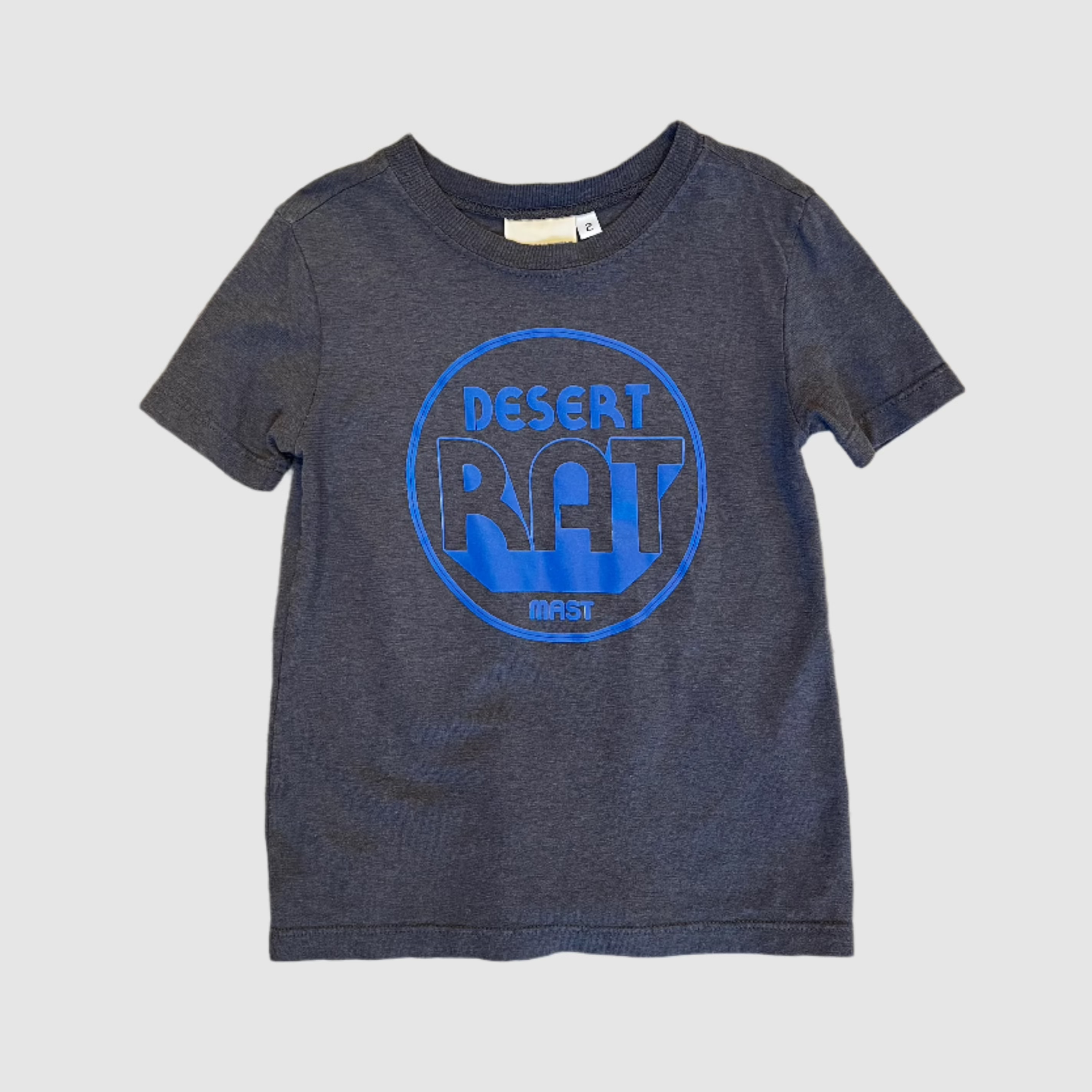 Front of a youth size, grey-blue colored t-shirt with "desert rat" circular, neon violet colored logo centered on shirt. Gray background
