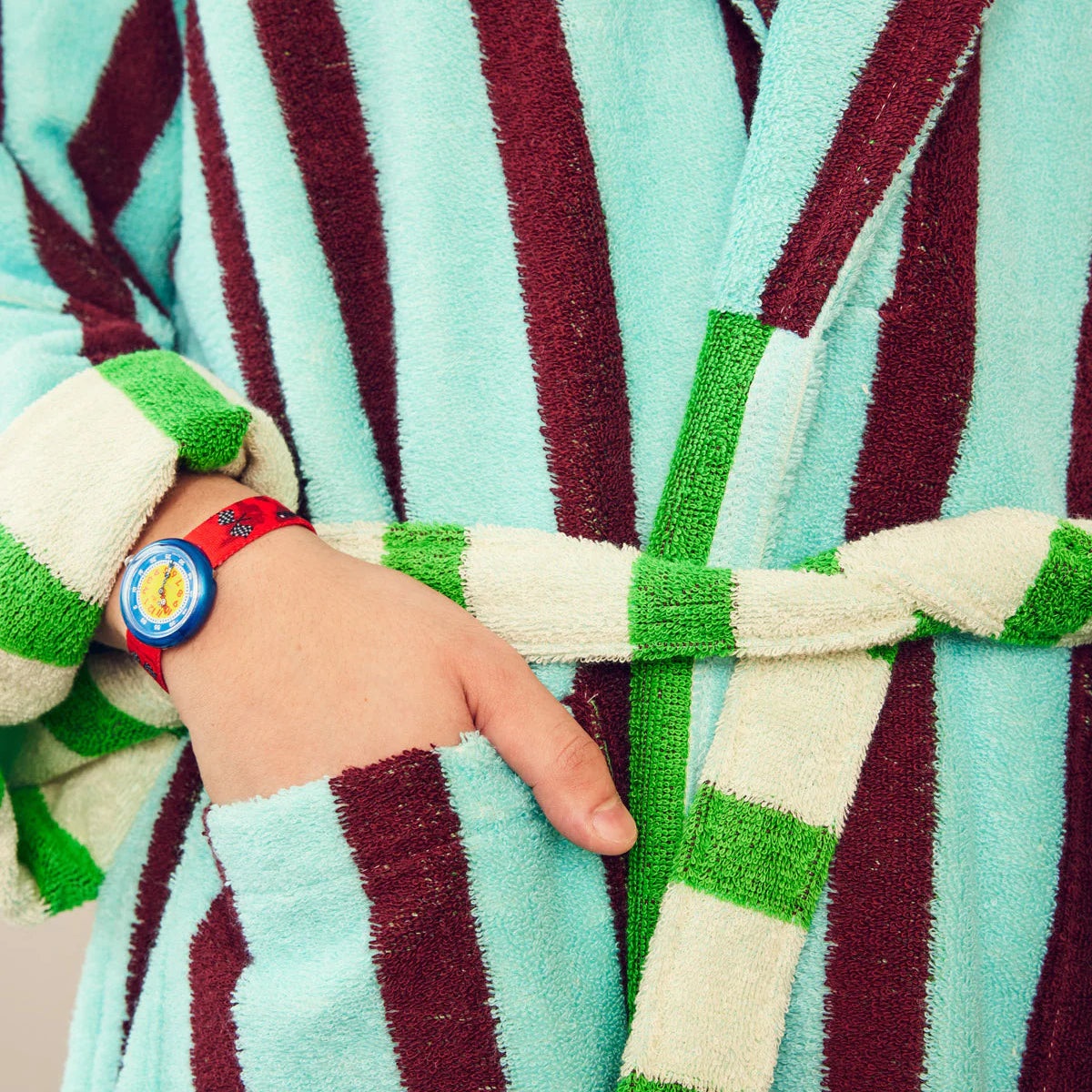Person wearing a striped robe with a colorful wristband on a blurred background