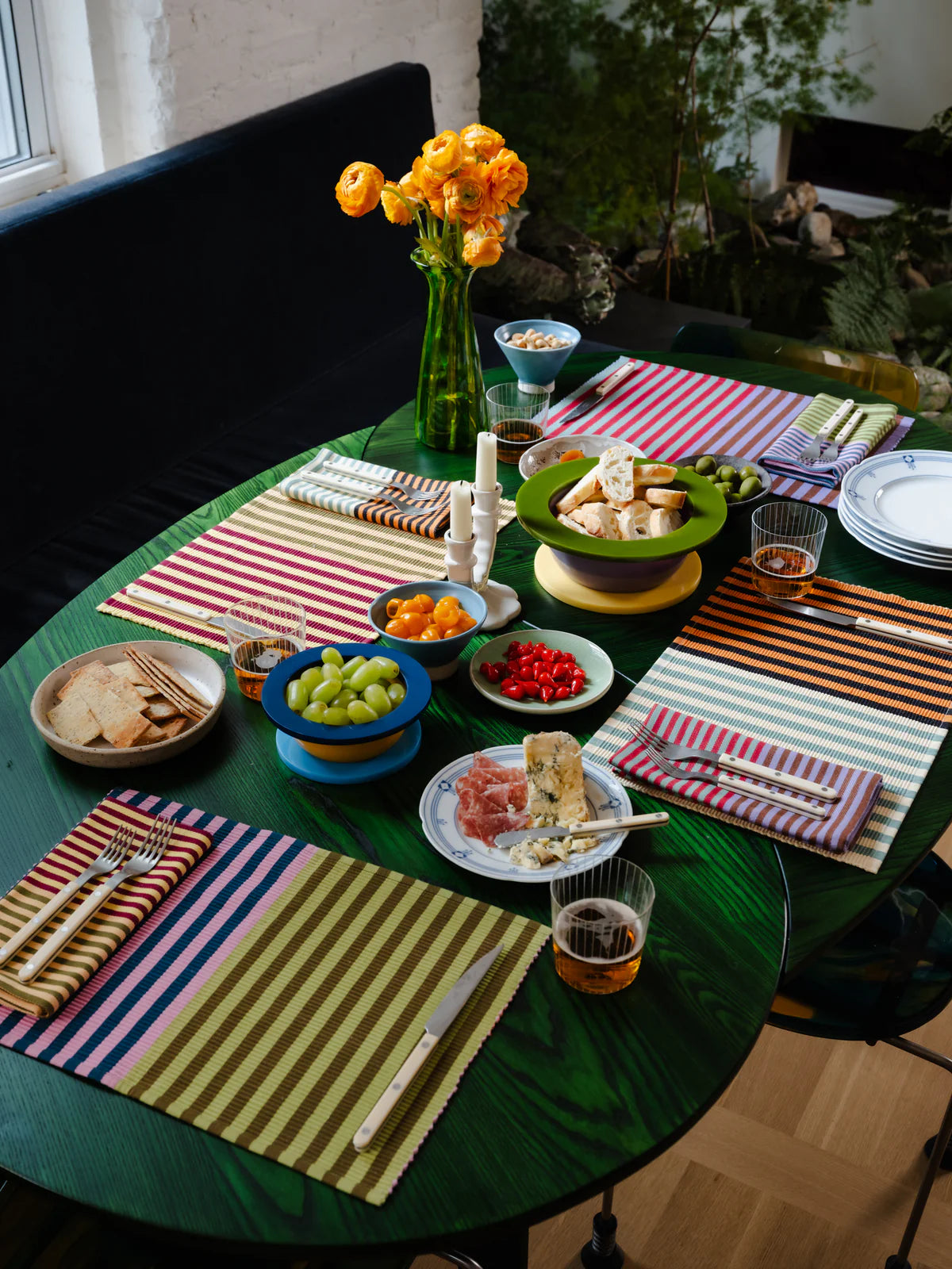 Dining table set with plates, glasses, and colorful placemats in a home setting showing off DusenDusen napkin set