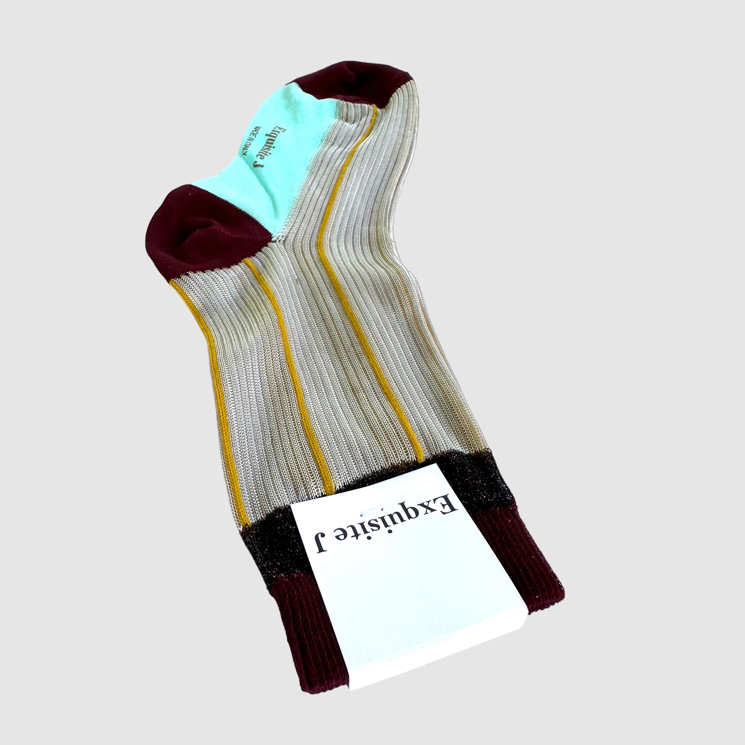 A pair of dress socks with a sheer cream and gold design, featuring solid turquoise and scarlet at the toe and heel areas.