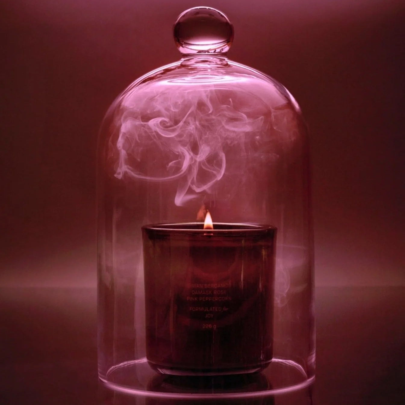 Candle inside a glass dome with smoke on a dark background