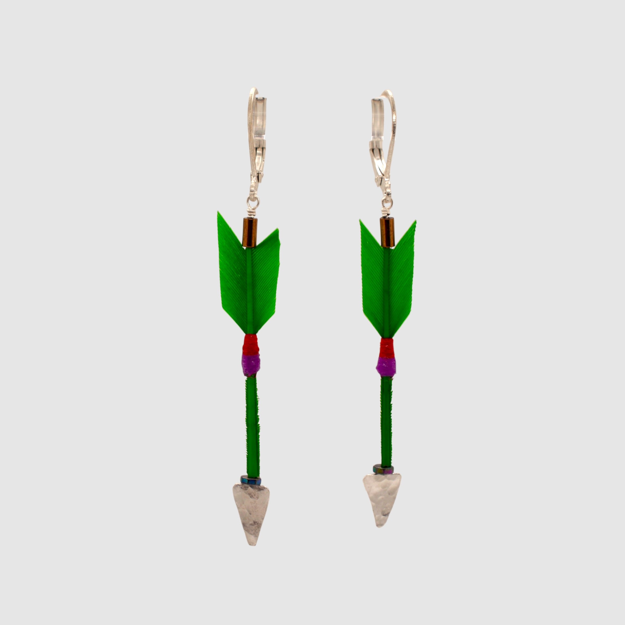 Green feather arrow earrings with vermeil arrowheads and leverback clasps designed and handmade in Tucson, Arizona by Sofie Albertsen. Displayed on a light grey background.