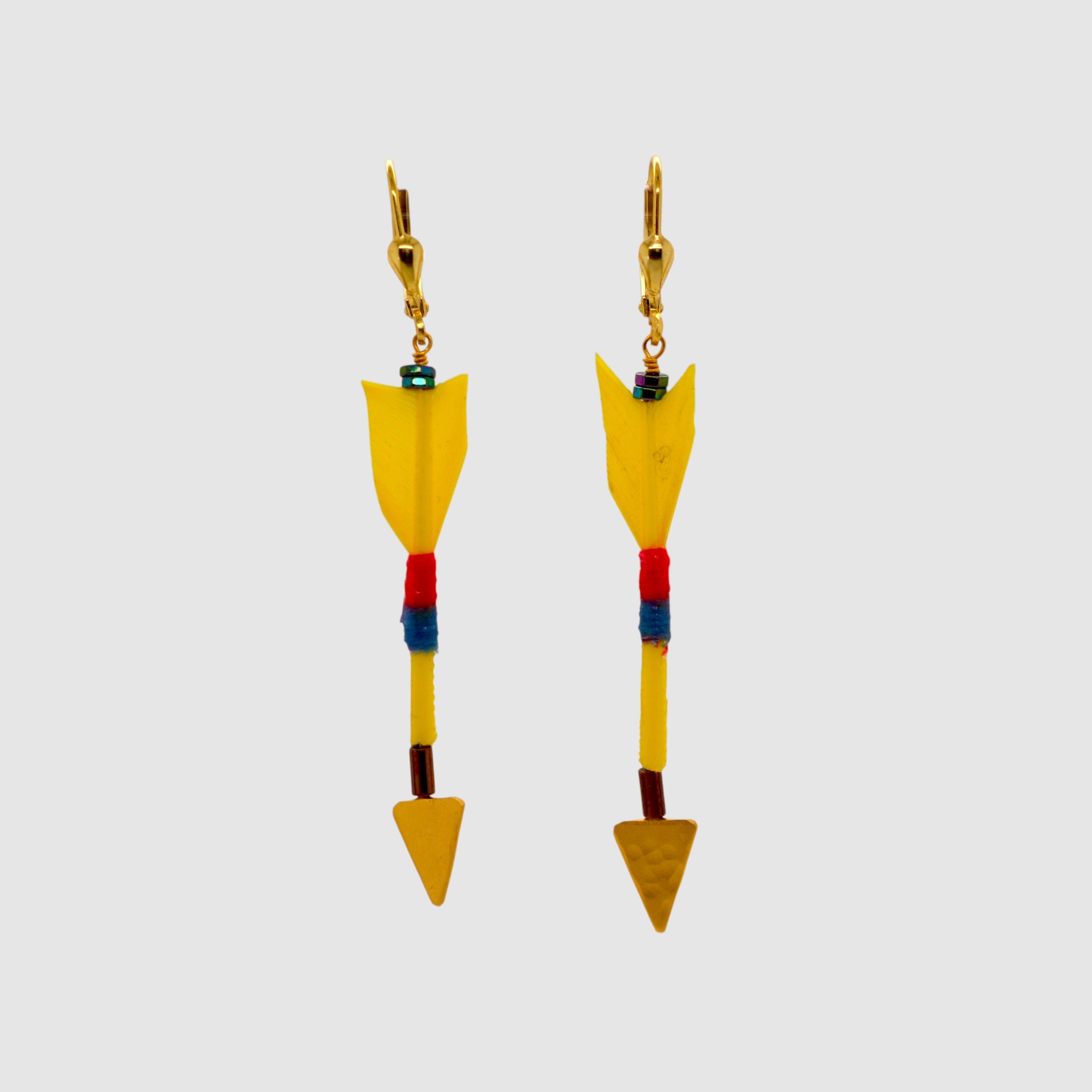 Yellow feather arrow earrings with vermeil arrowheads and leverback clasps designed and handmade in Tucson, Arizona by Sofie Albertsen. Displayed on a light grey background.