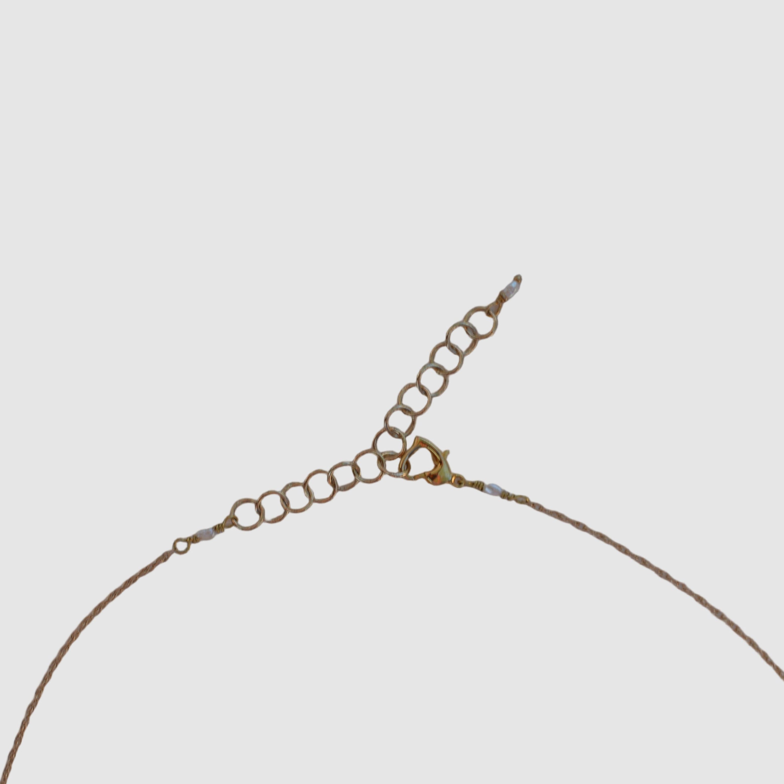 clasp view of gold chain necklace on light grey background