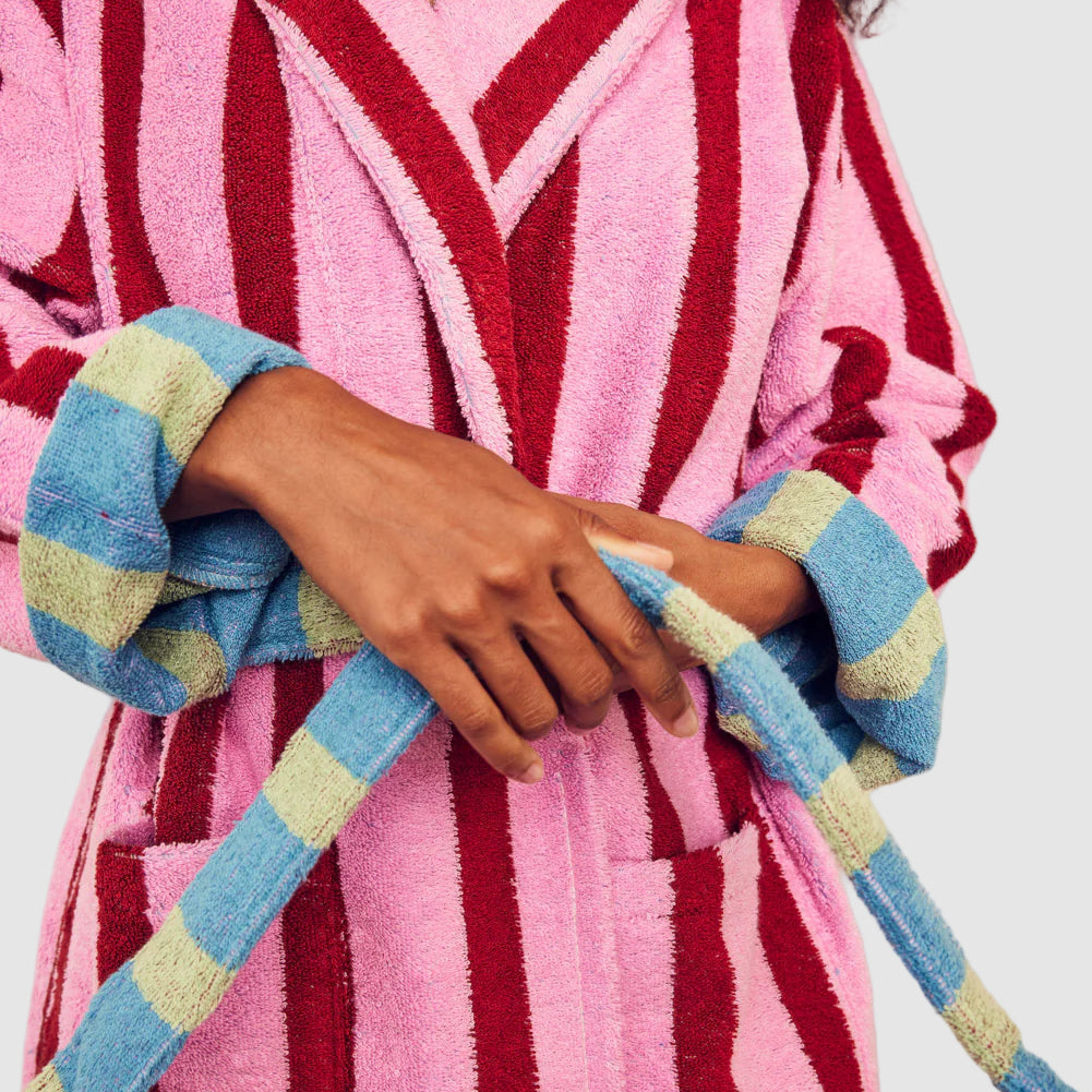 Person wearing a pink and red striped robe with a colorful towel.