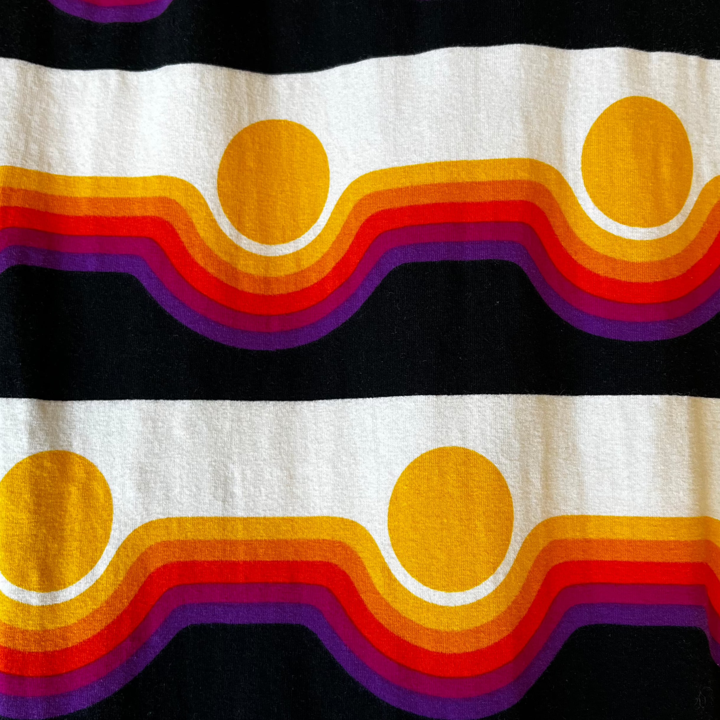 Close-up of Noowork's "Circa" pattern featuring yellows, oranges, reds, purples, and blacks in a geometric sunset resembling pattern.