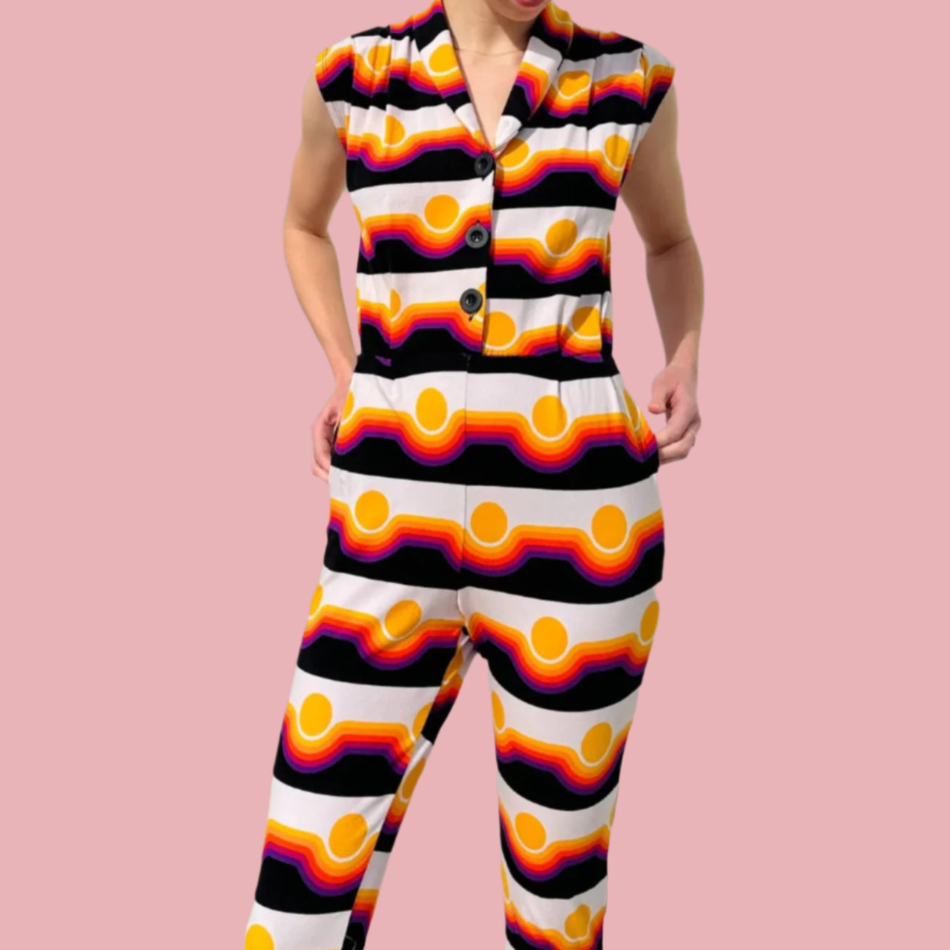 Noowork's "Circa" pattern featuring yellows, oranges, reds, purples, and blacks in a geometric style resembling a sunset in the "magic suit" form styled on a young woman. Light pink background.