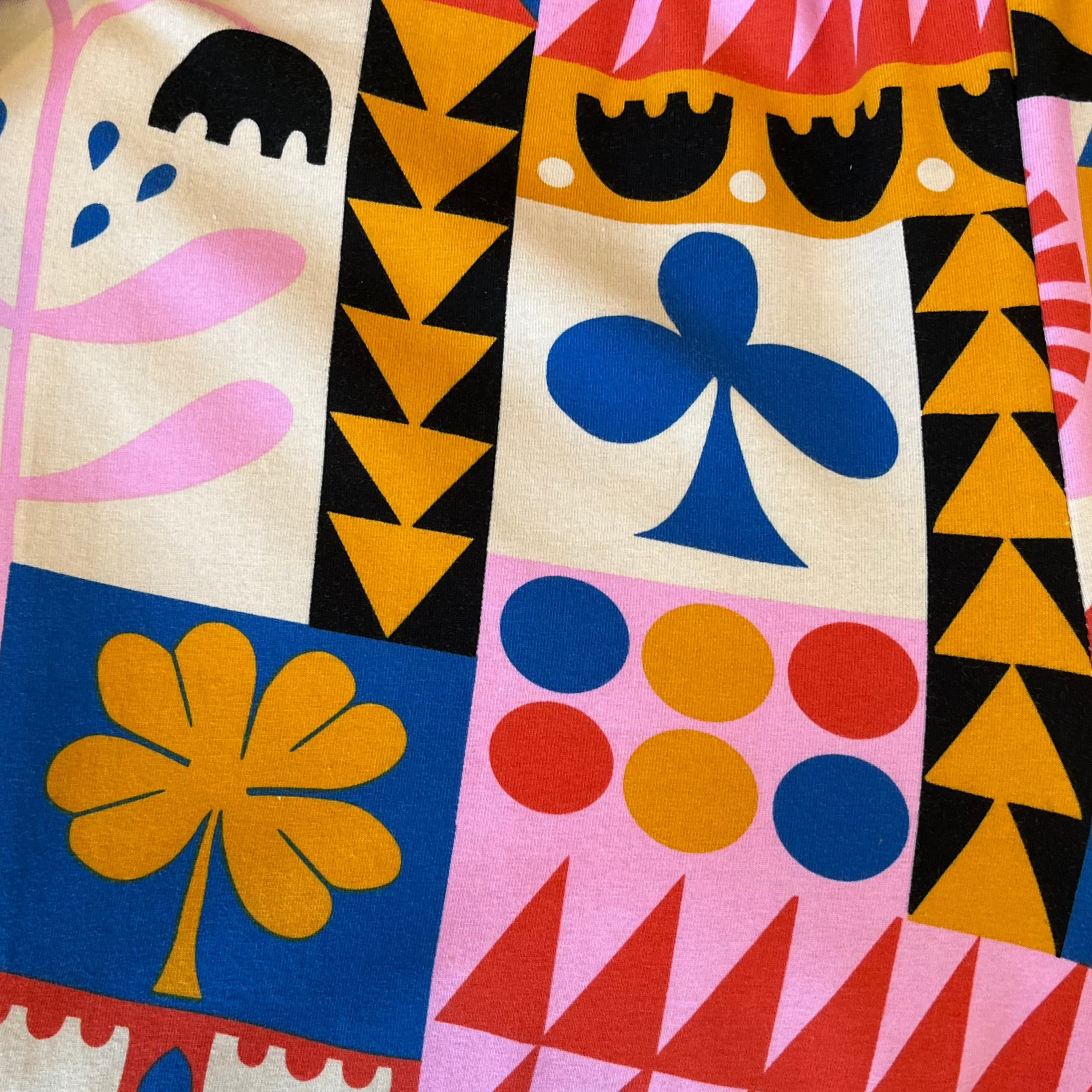 Close-up of "Congdon" pattern. Geometric-like pattern of blue, yellow, pink, red, white, and black printed on cotton.