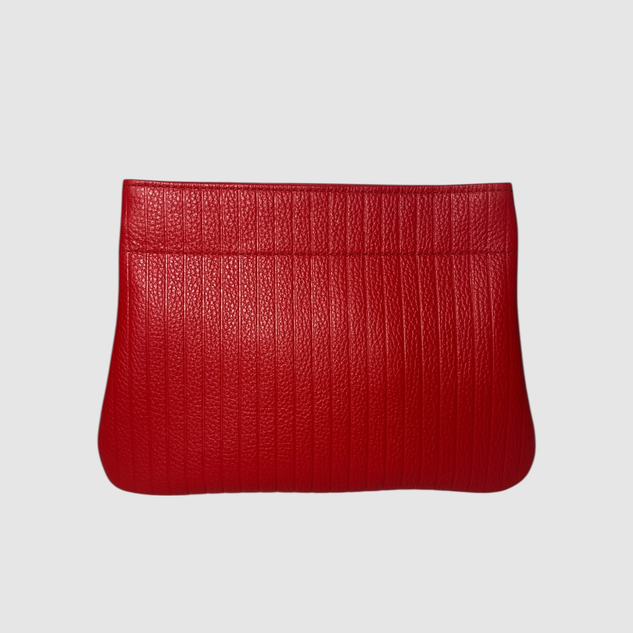Embossed cherry red handmade leather clutch on a light grey background. Bag made by Mellow Dawn in Tucson, Arizona.