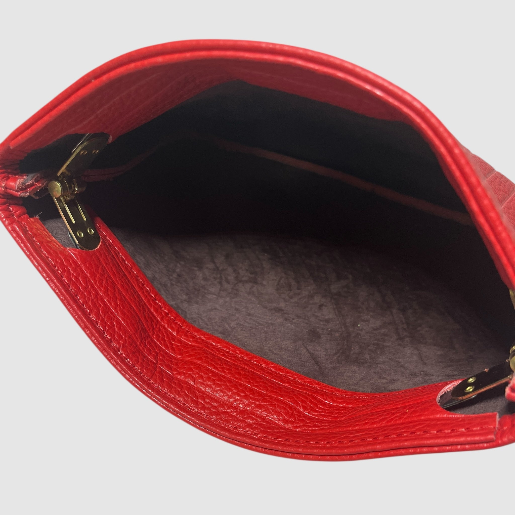 Suede interior of an embossed cherry red handmade leather clutch on a light grey background. Bag made by Mellow Dawn in Tucson, Arizona.