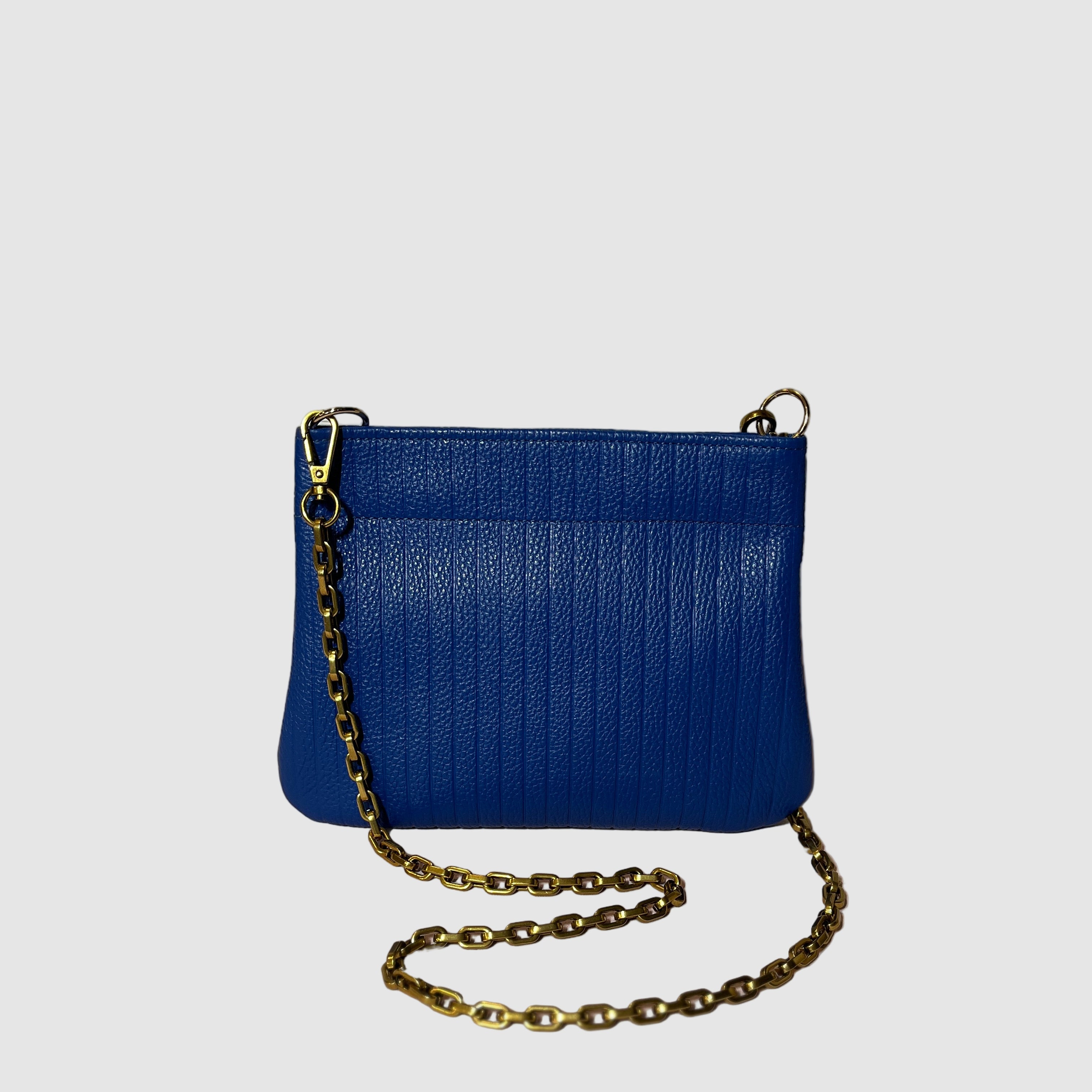 Embossed cobalt blue handmade leather handbag with curb chain strap on a light grey background. Bag made by Mellow Dawn in Tucson, Arizona.