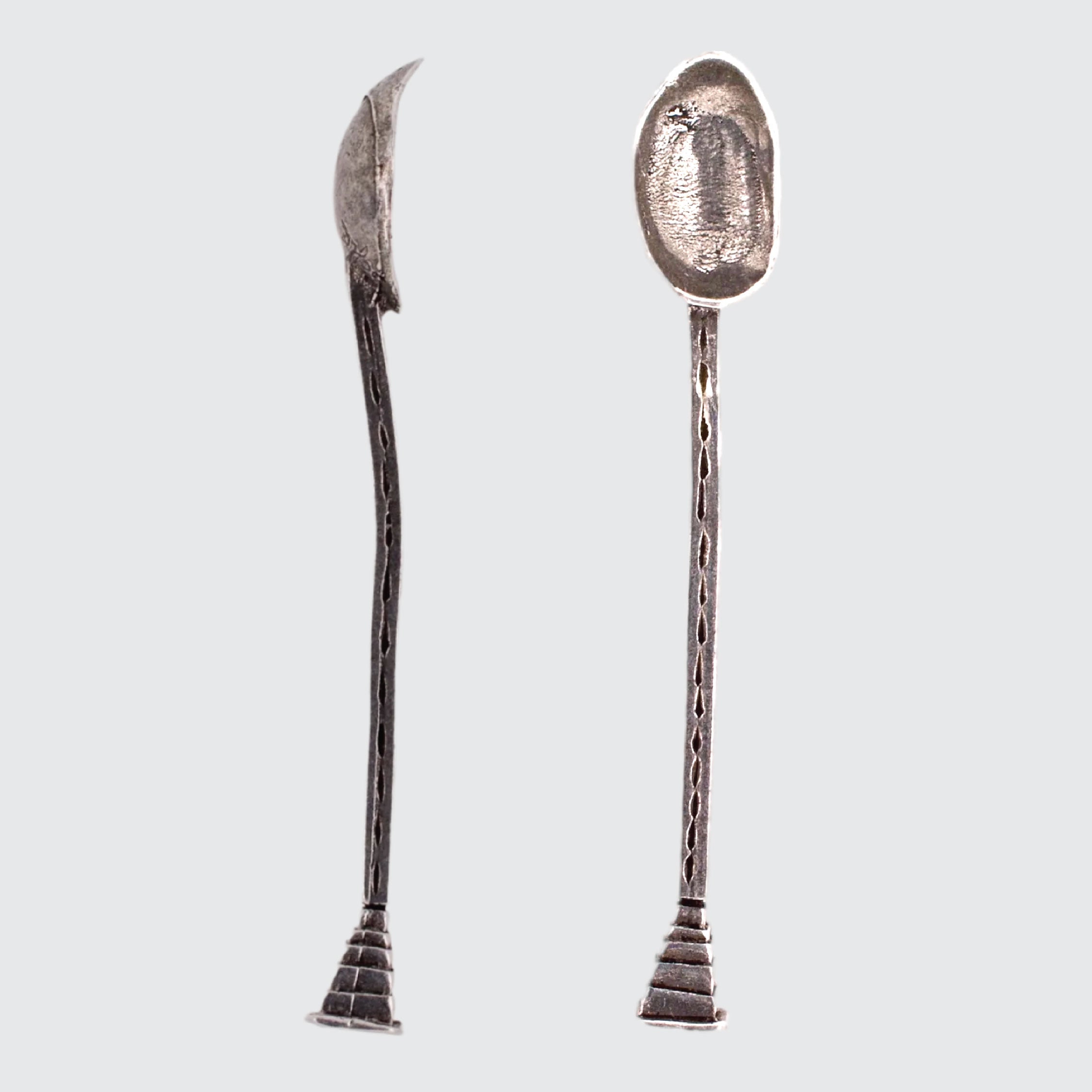 Two silver spoons with unique designs on a light gray background