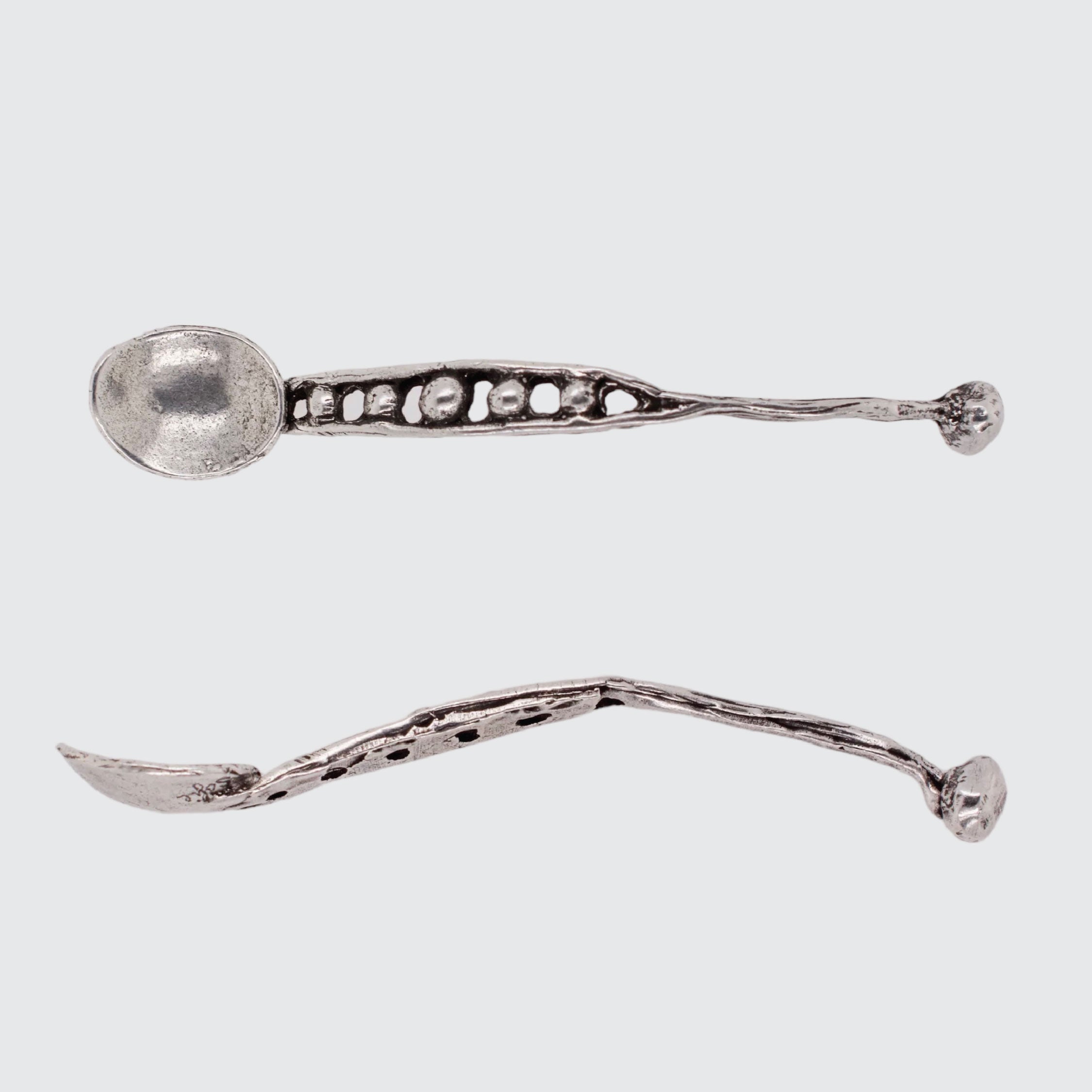 Two silver spoons with decorative handles on a light gray background