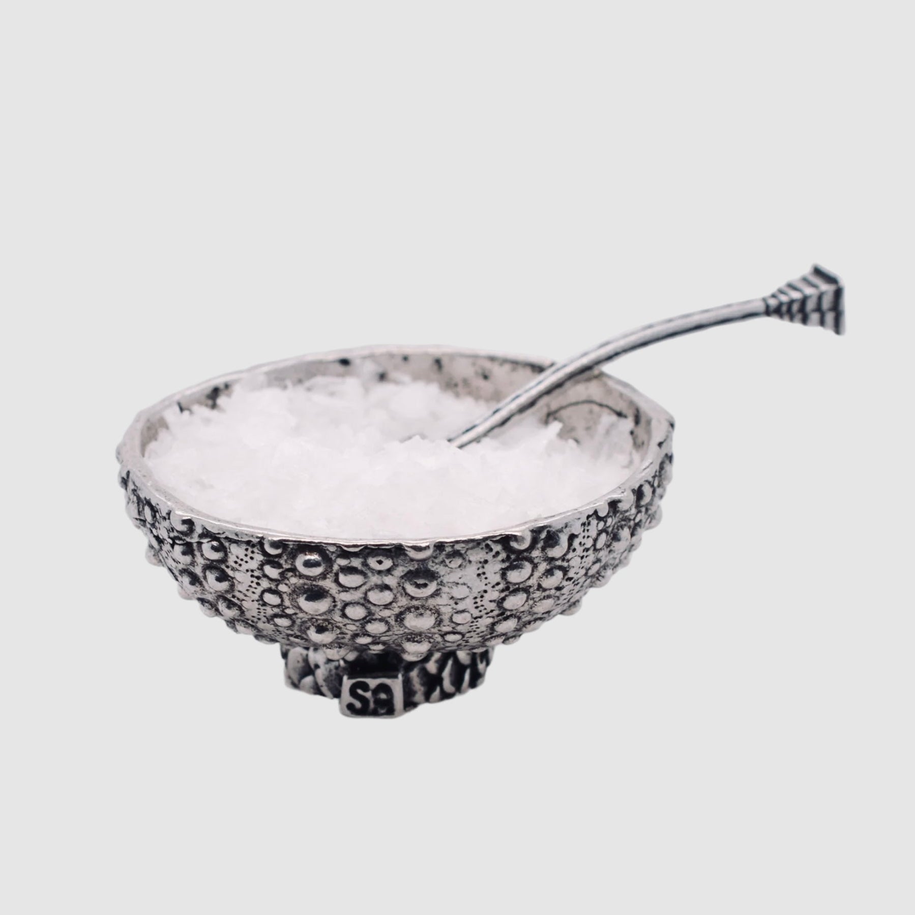 Decorative salt cellar with a spoon on a light gray background