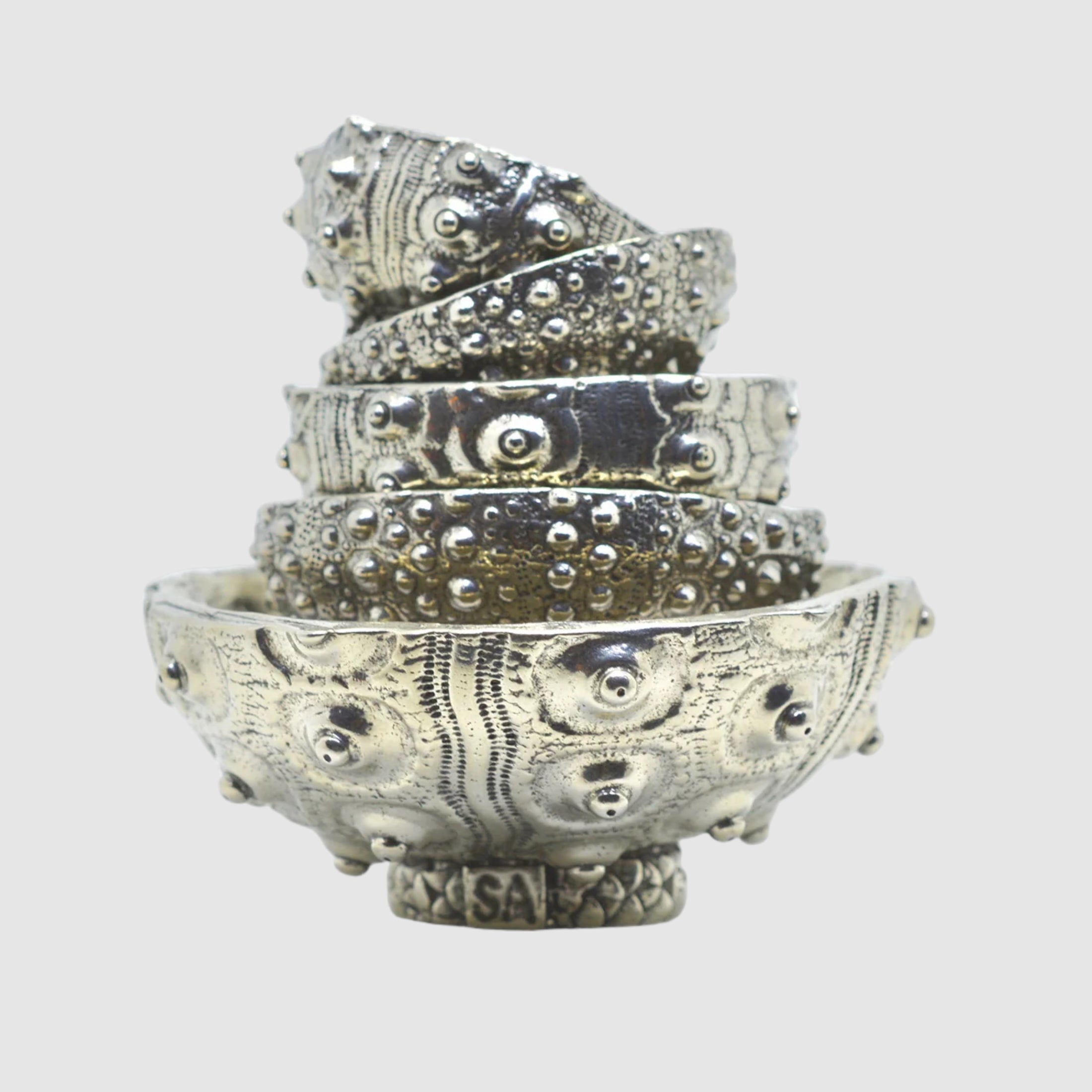 A set of five silver-colored pewter bowls of varying sizes, designed with sea urchin-like patterns.