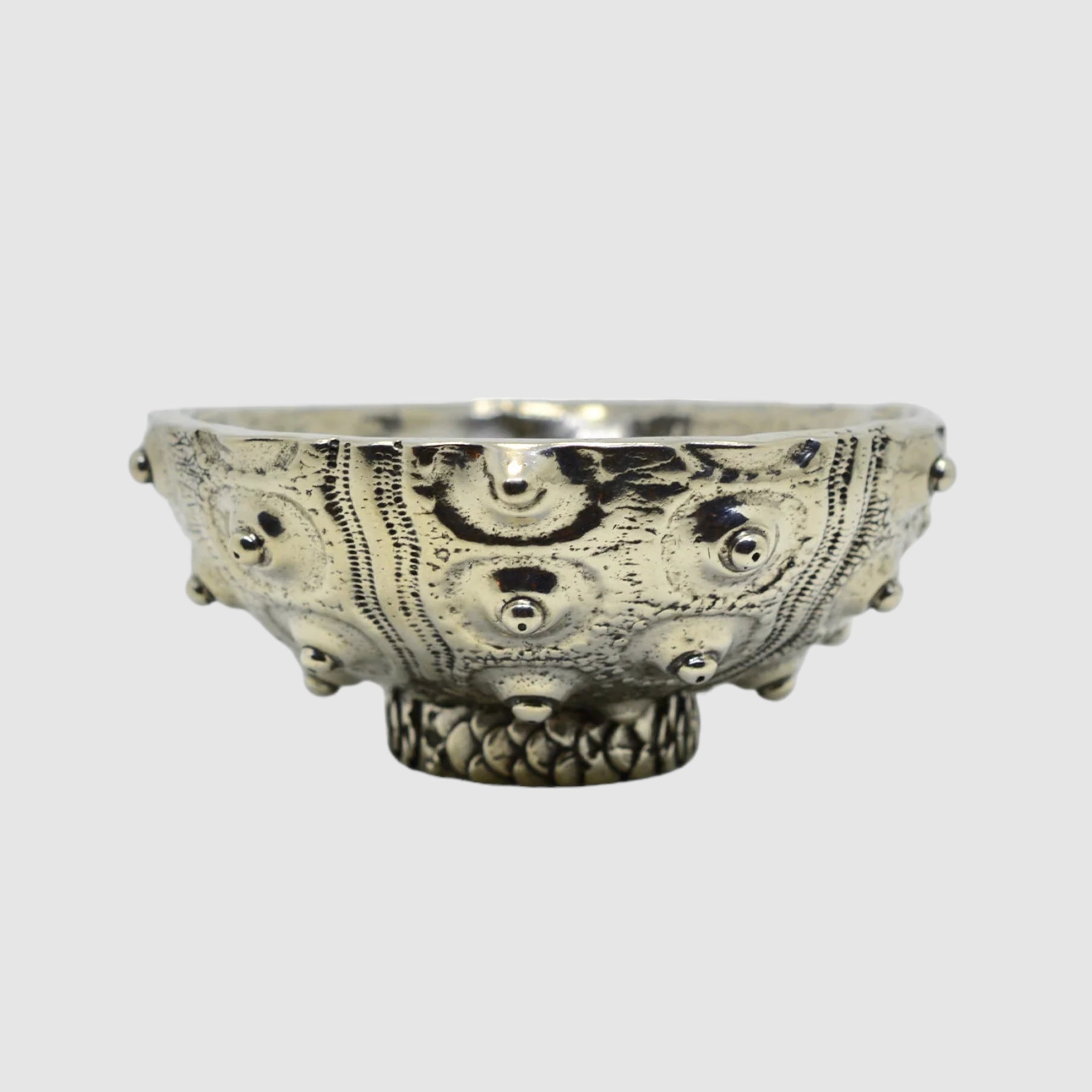 This image features a striking pewter bowl known as the SEA URCHIN BOWL // SPUTNIK // LARGE, crafted by SOFIE ALBERTSEN in Tucson. The bowl stands out with its unique sea urchin-inspired texture and pattern, encompassing intricate designs and protruding elements that add a tactile quality to the piece.