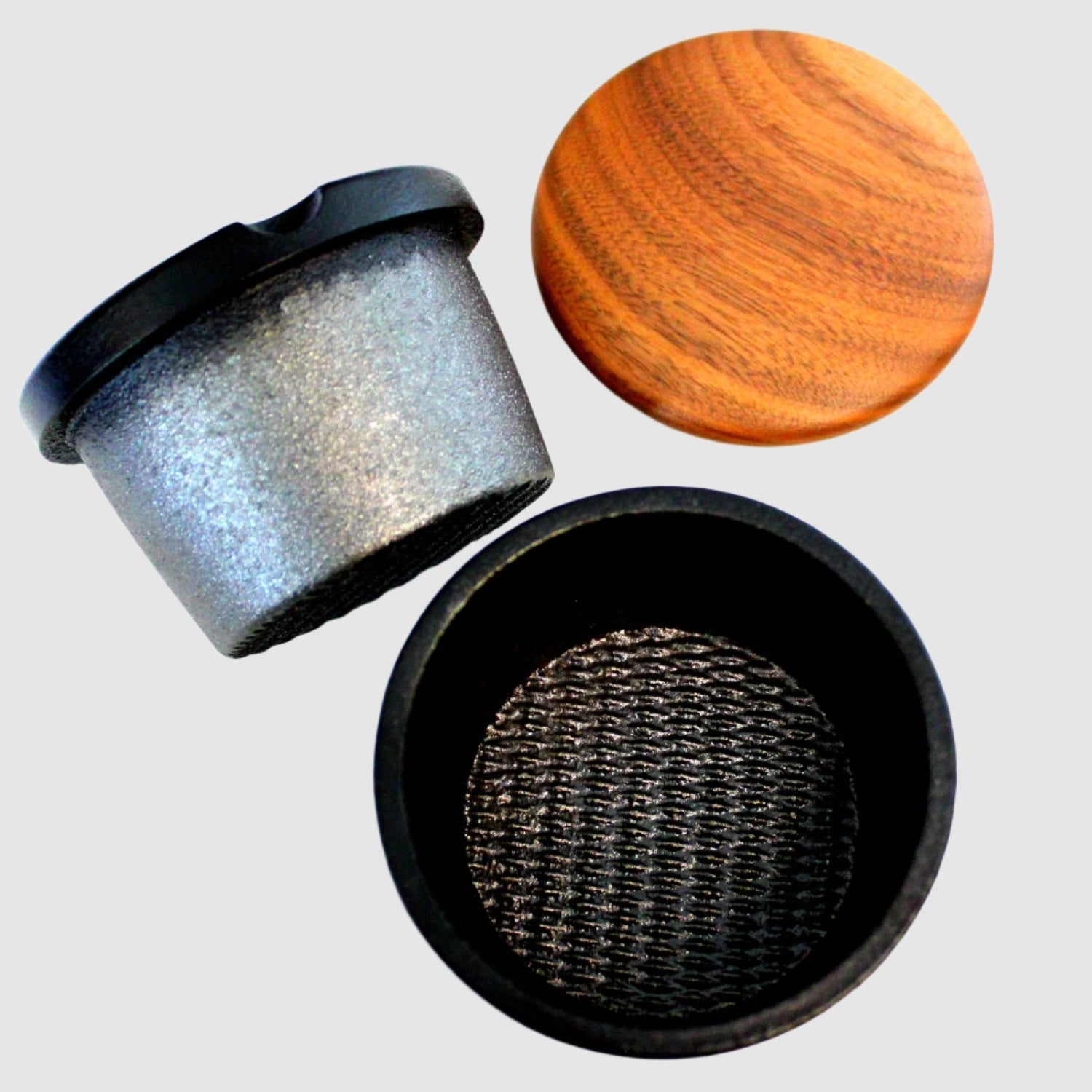 Metallic mesh filter with wooden lid and black container on a white background