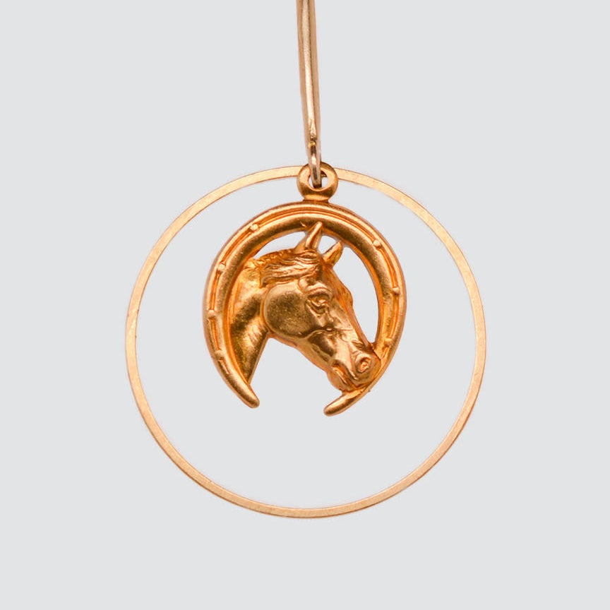 Gold horse head earrings on a light gray background