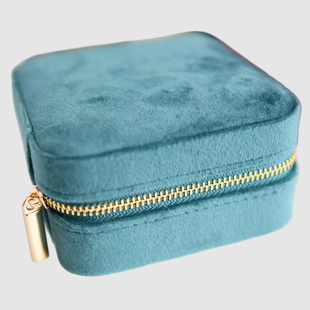 A closed, teal, velvet, Cecelia Designs jewelry travel case with compartments for rings, bracelets, necklaces, on a light background. The perfect, unique gift for a jewelry lover.