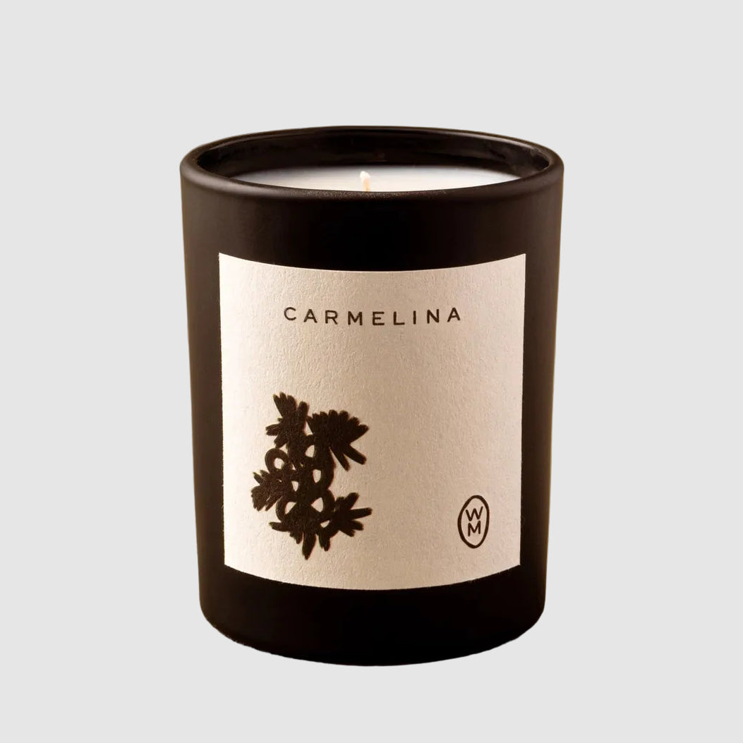 Candle in a black container with a label on a beige background