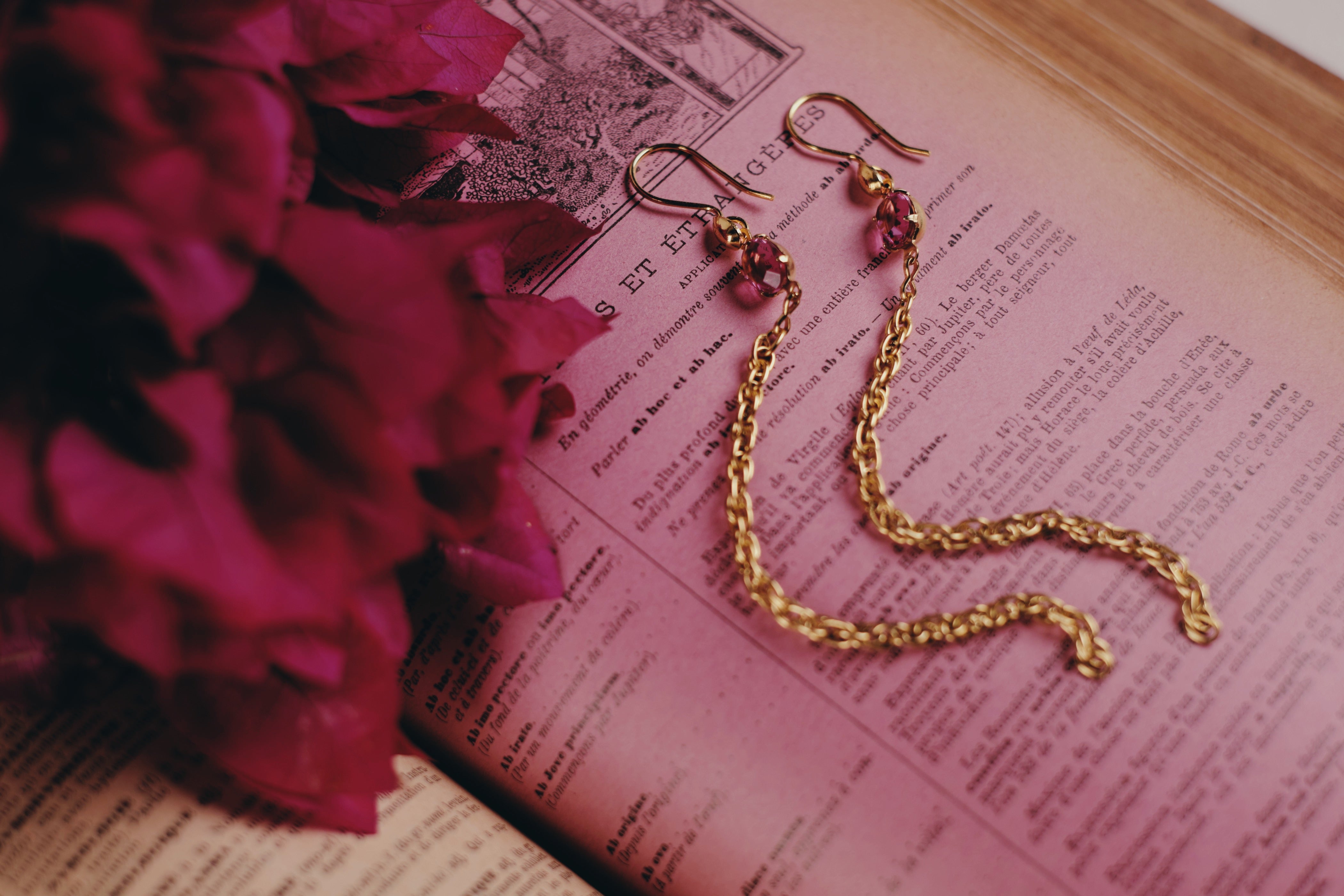 vermeil french wires with swarovski crystal drop and brass chain drop earrings handmade in Tucson by Tasha Bundy sitting on a book with some pinkish tint