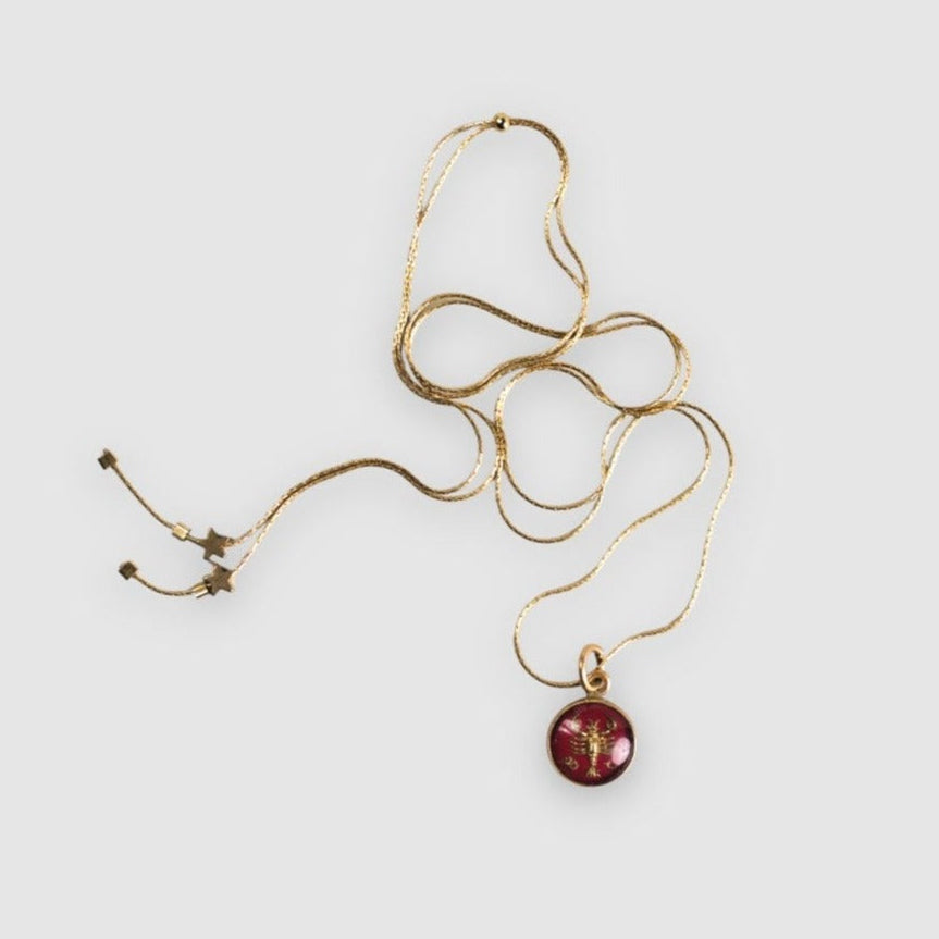 A vintage 1950's German Cancer Intaglio pendant necklace set in brass, on a gold-filled snake chain with an adjustable clutch closure, finished with tiny brass star accent beads.