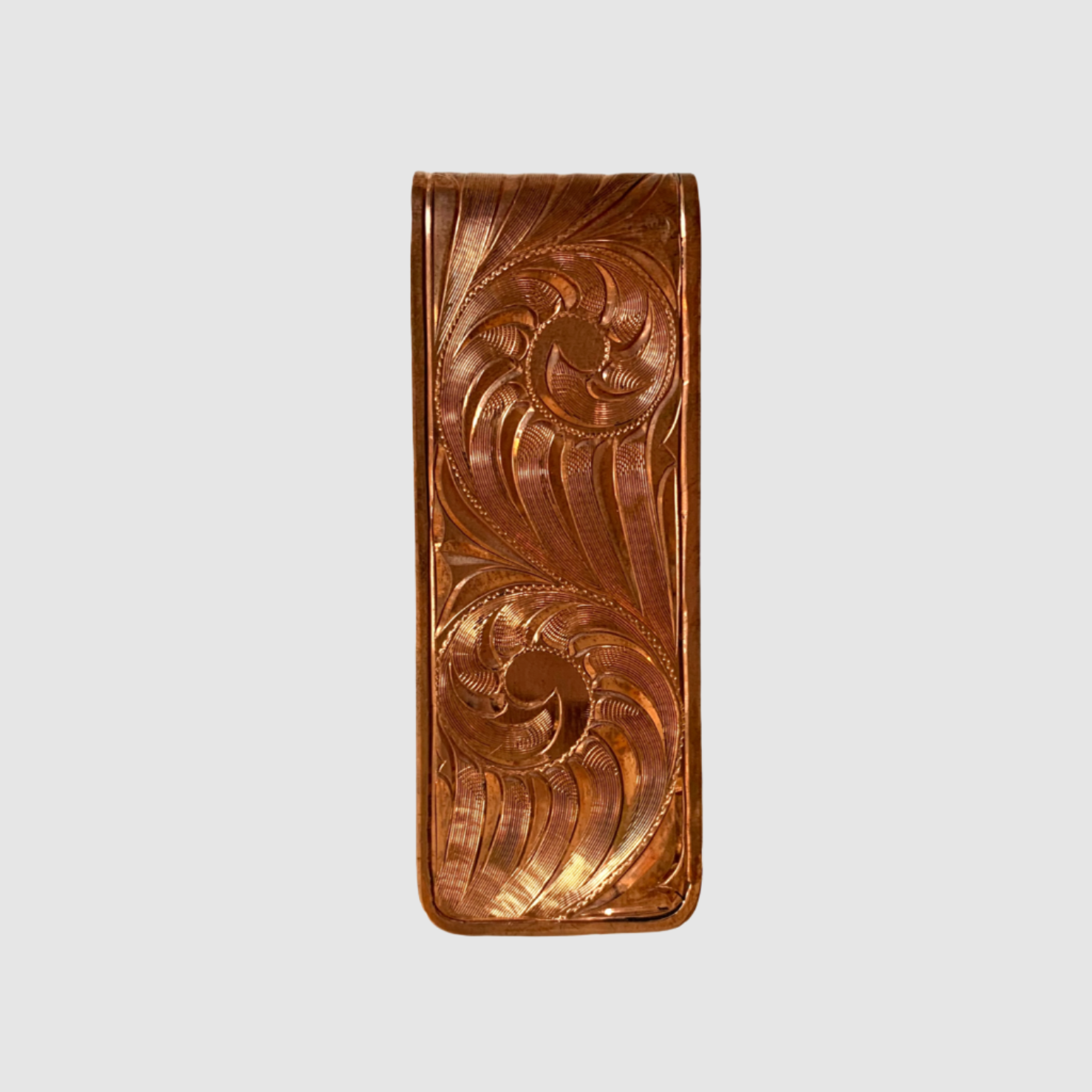 copper money clip with intricate carvings on a white background