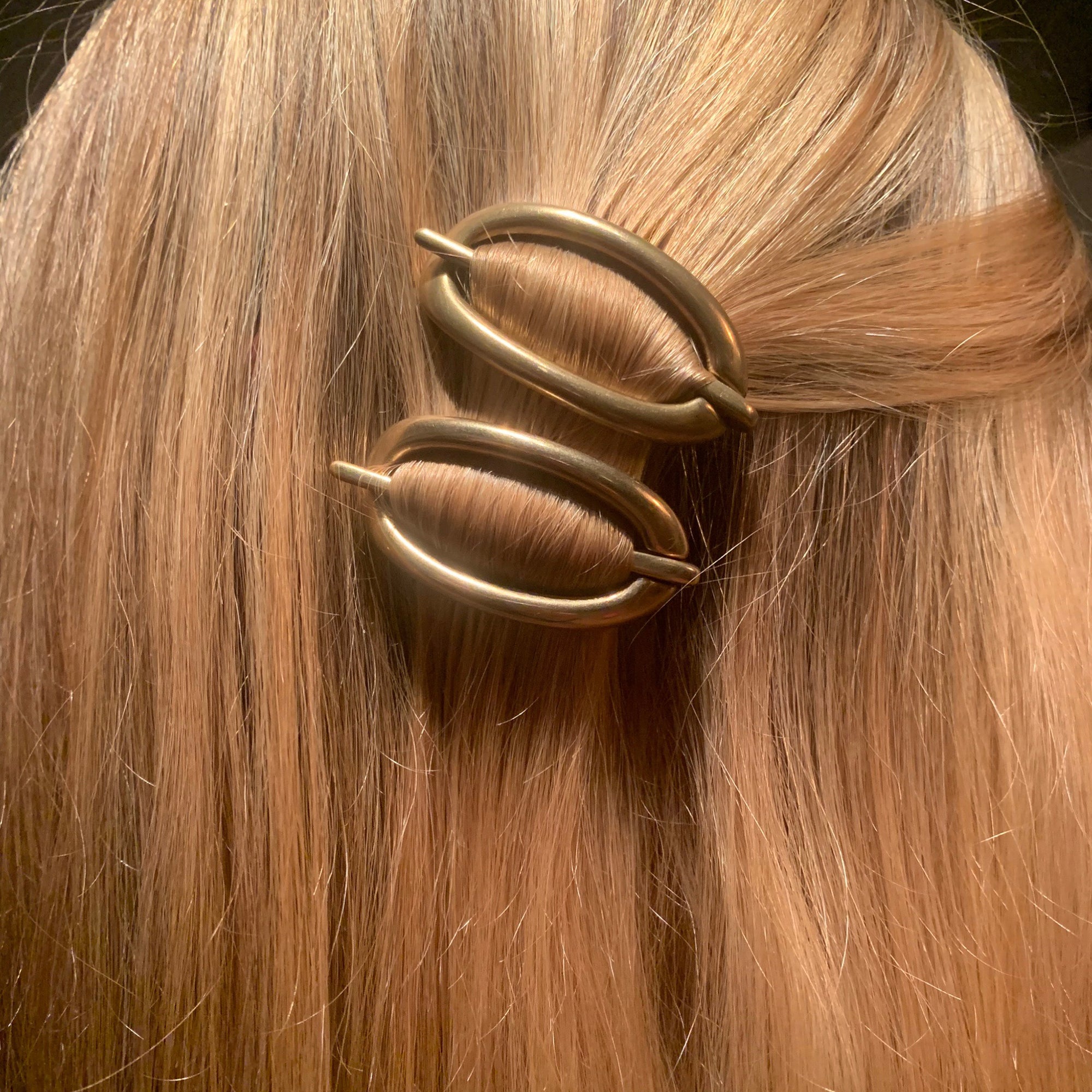 A pair of bronze Danish hair clips in a young person's blonde hair.